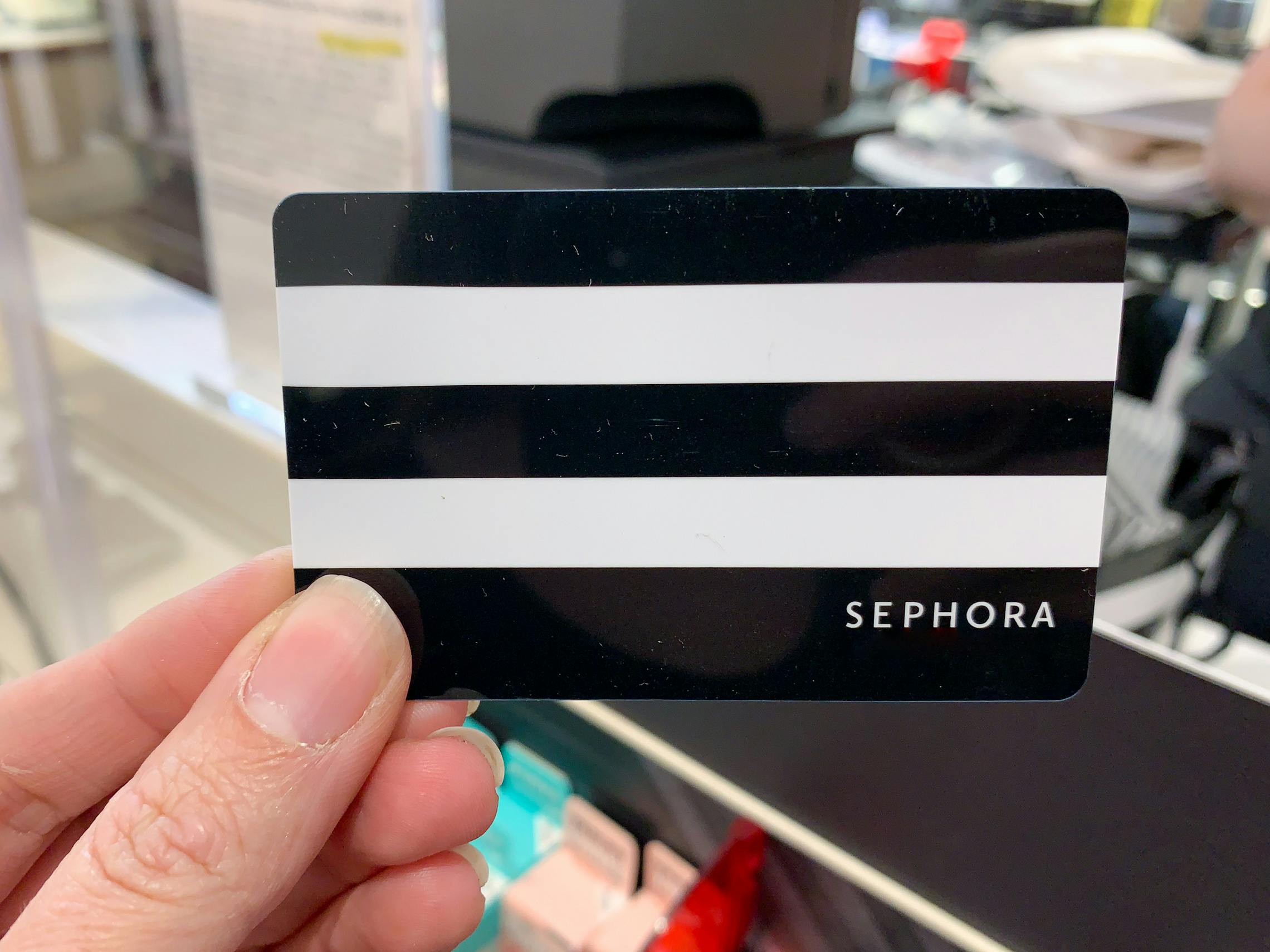 A person holding up a Sephora gift card