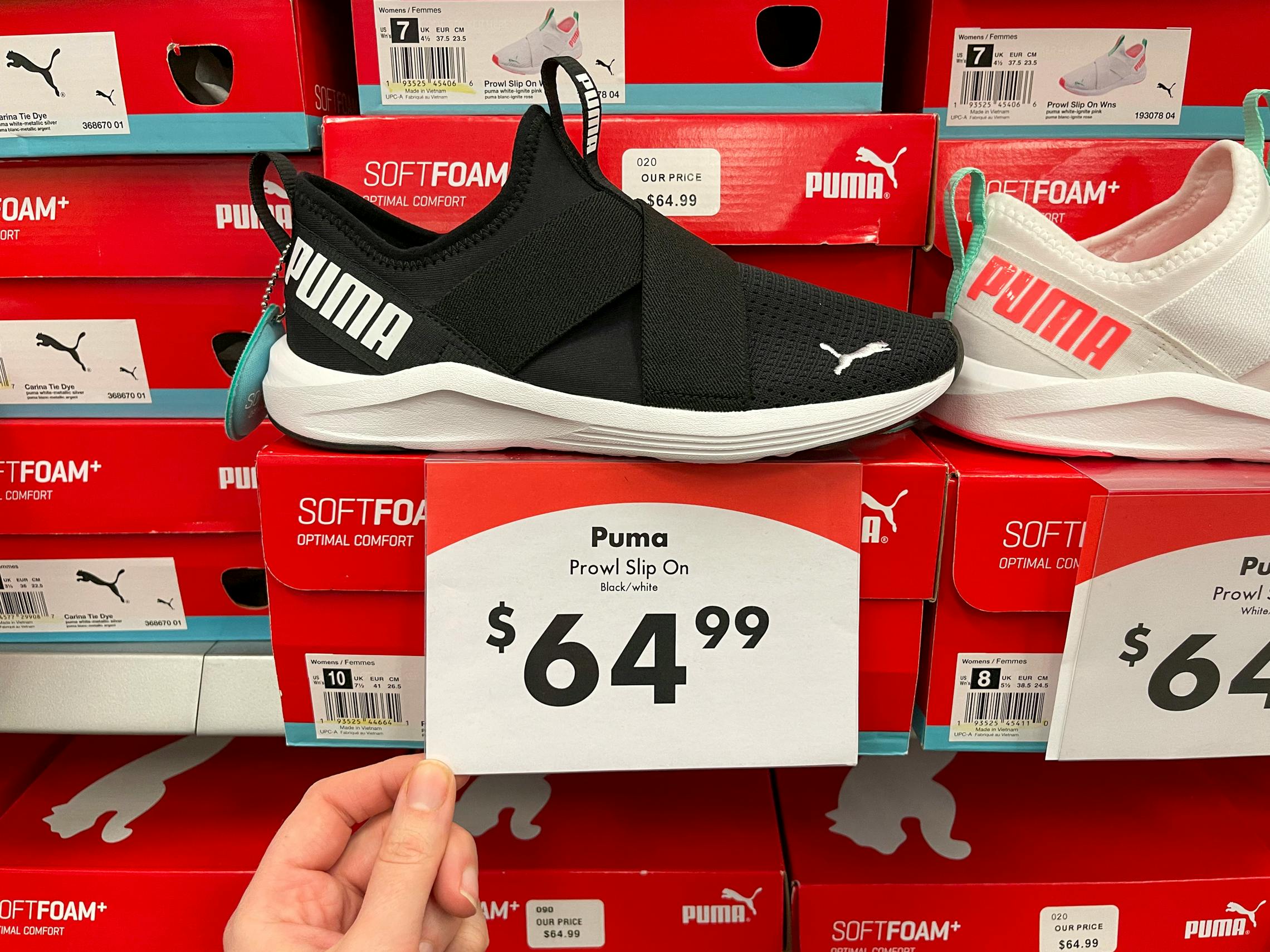 A pair of Puma running shoes on a shelf with shoe boxes and a price tag reading, "$64.99".