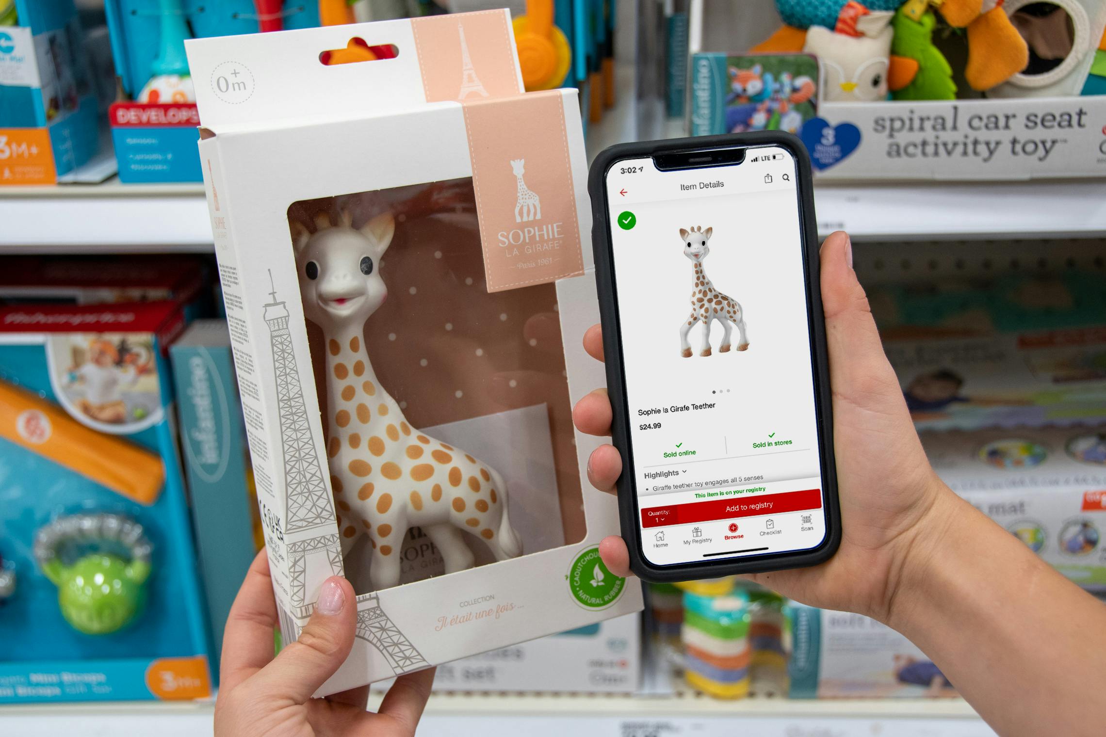 A toy giraffe held next to the Target registry app displaying that item.