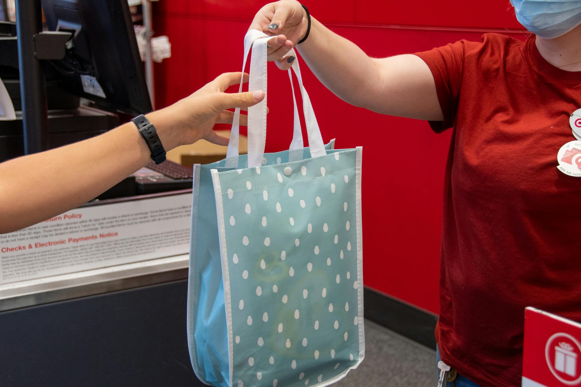 A Target employee handing a woman a free baby gift bag. 