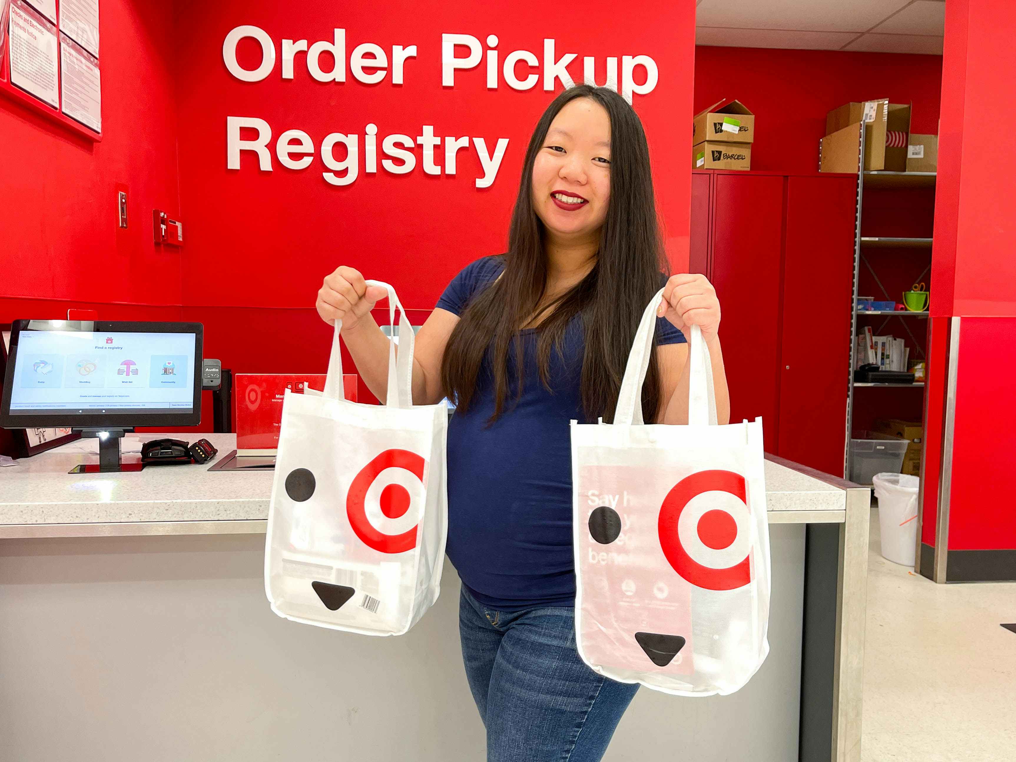 a woman holding up two target baby registry welcome bags