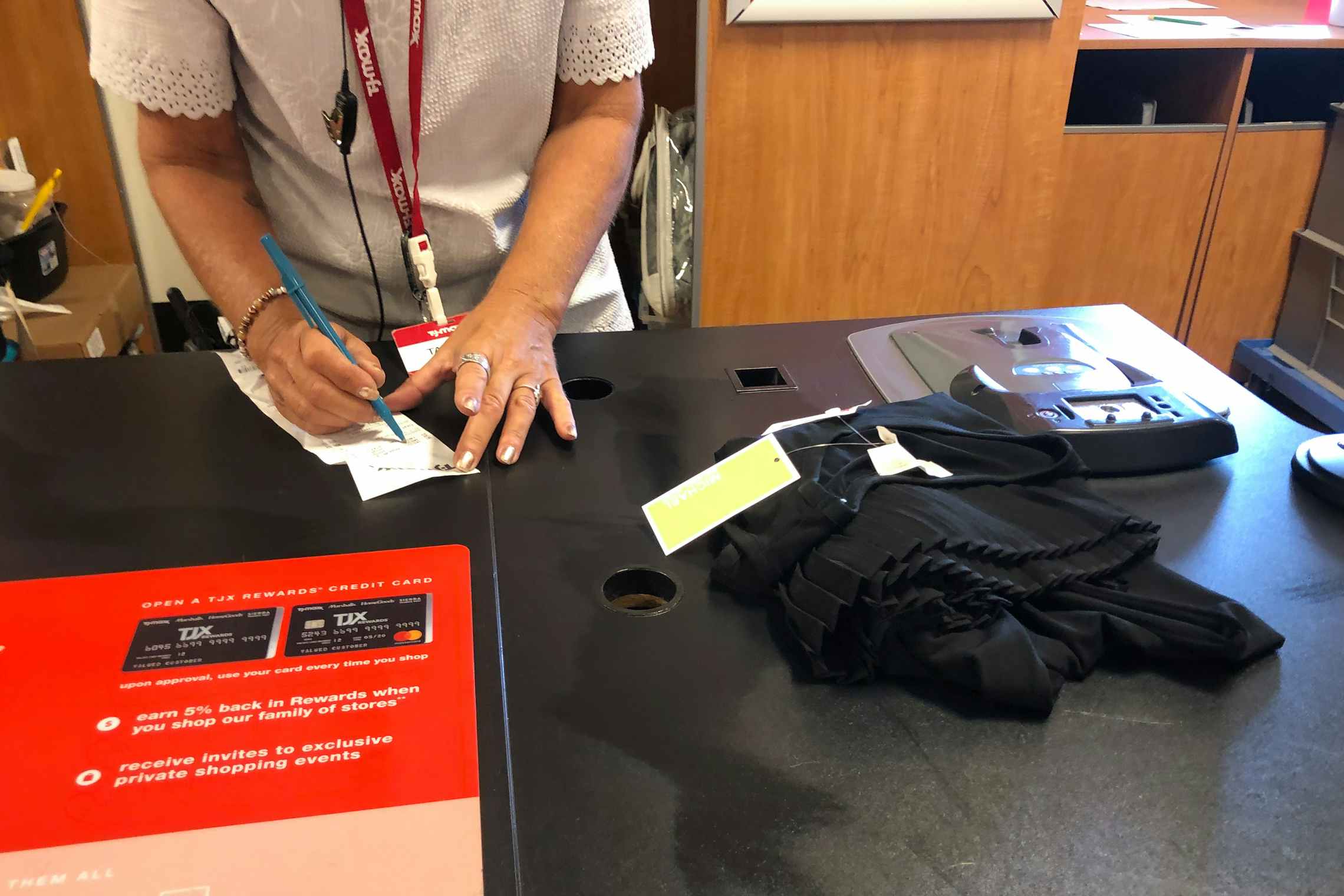 An item of clothing on the counter at TJ Maxx with an employee writing on a receipt