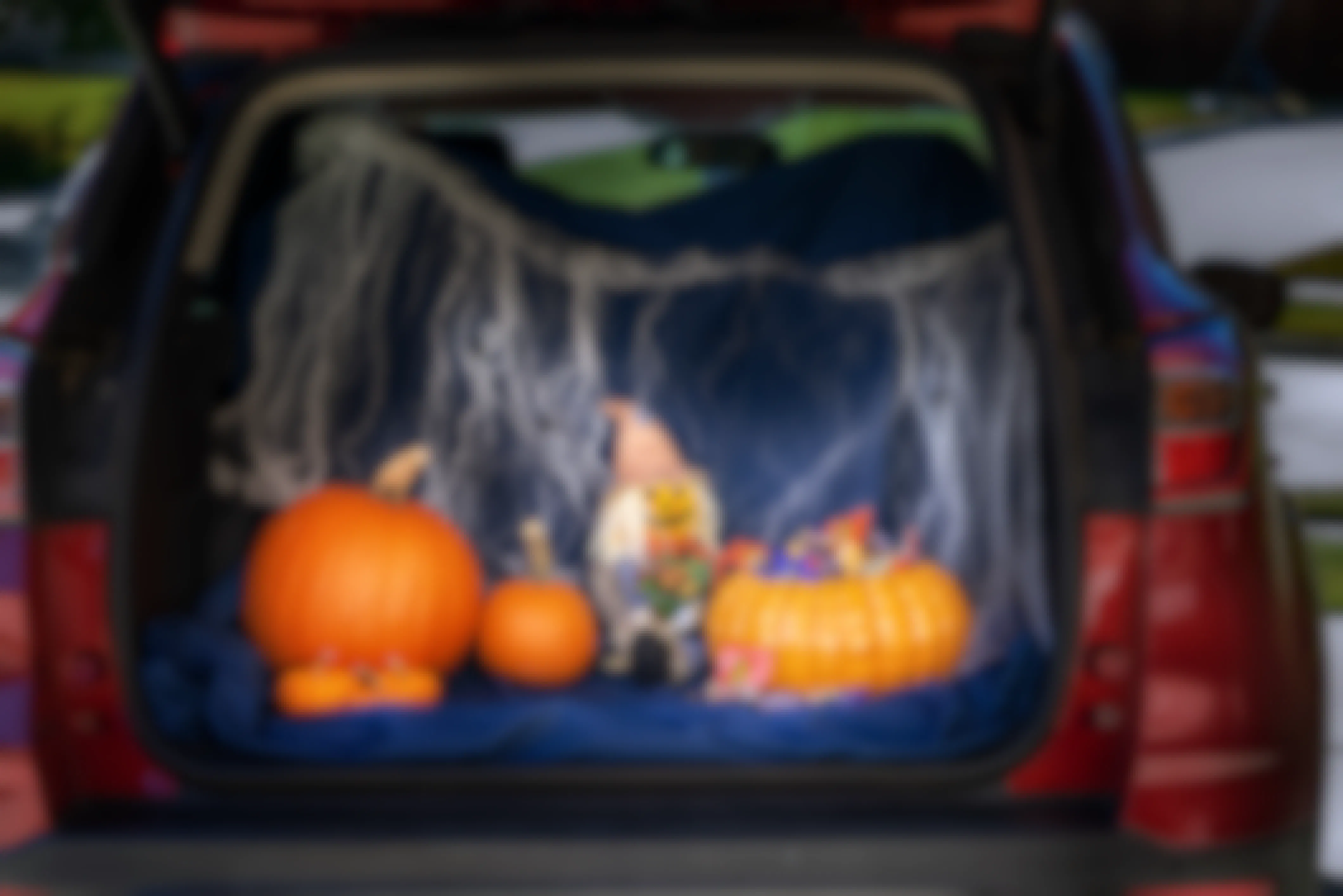 Trunk of vehicle open with halloween decorations and candy inside it