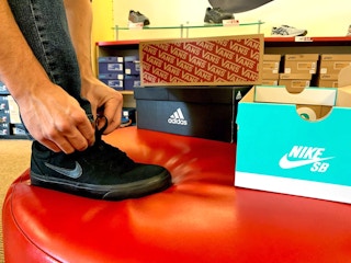 Man tying his shoe while trying on shoes at famous footwear