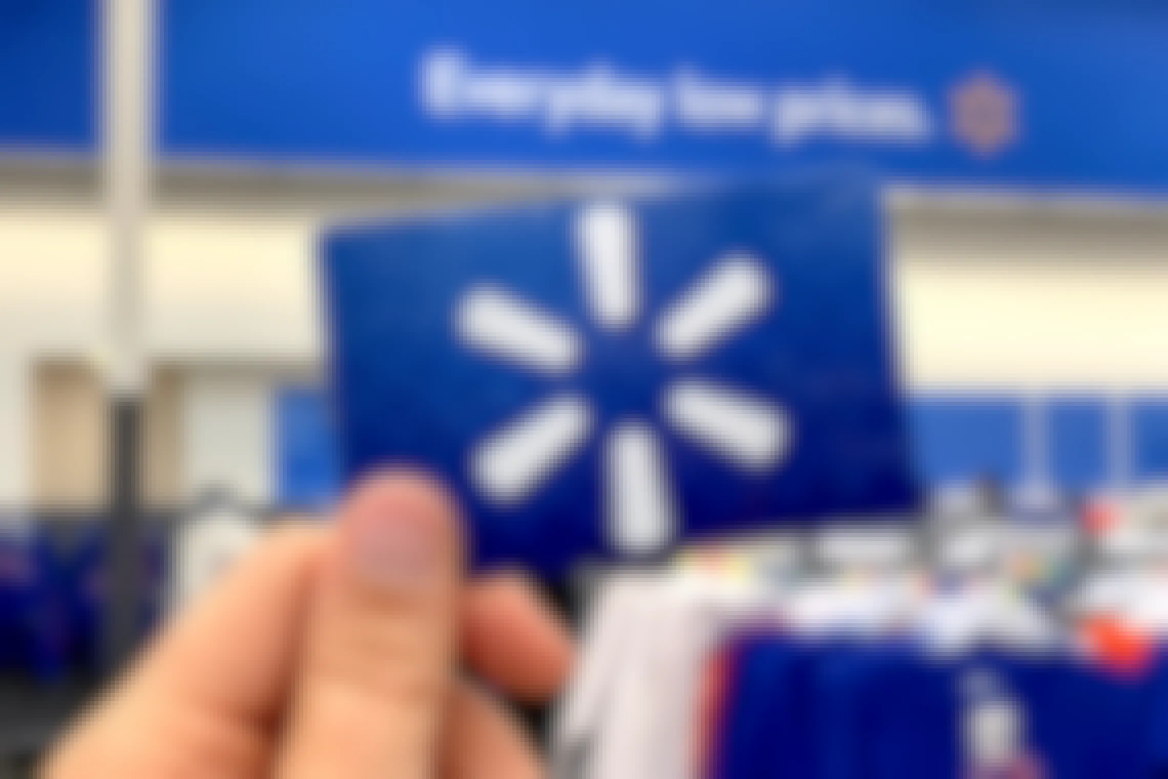 Walmart gift card held up in store with Walmart logo in background