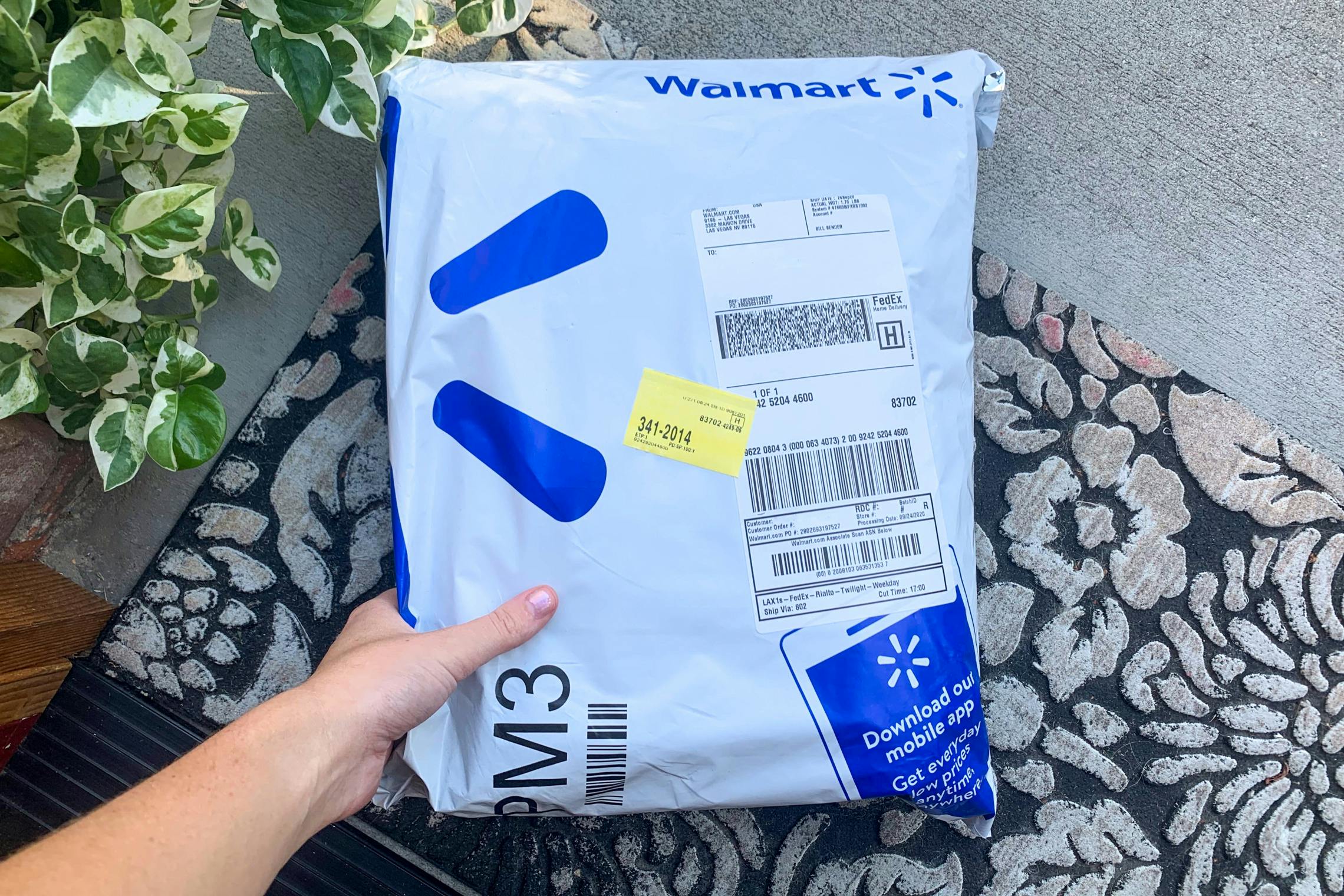 A person picking up an Walmart online delivery package from their front porch.