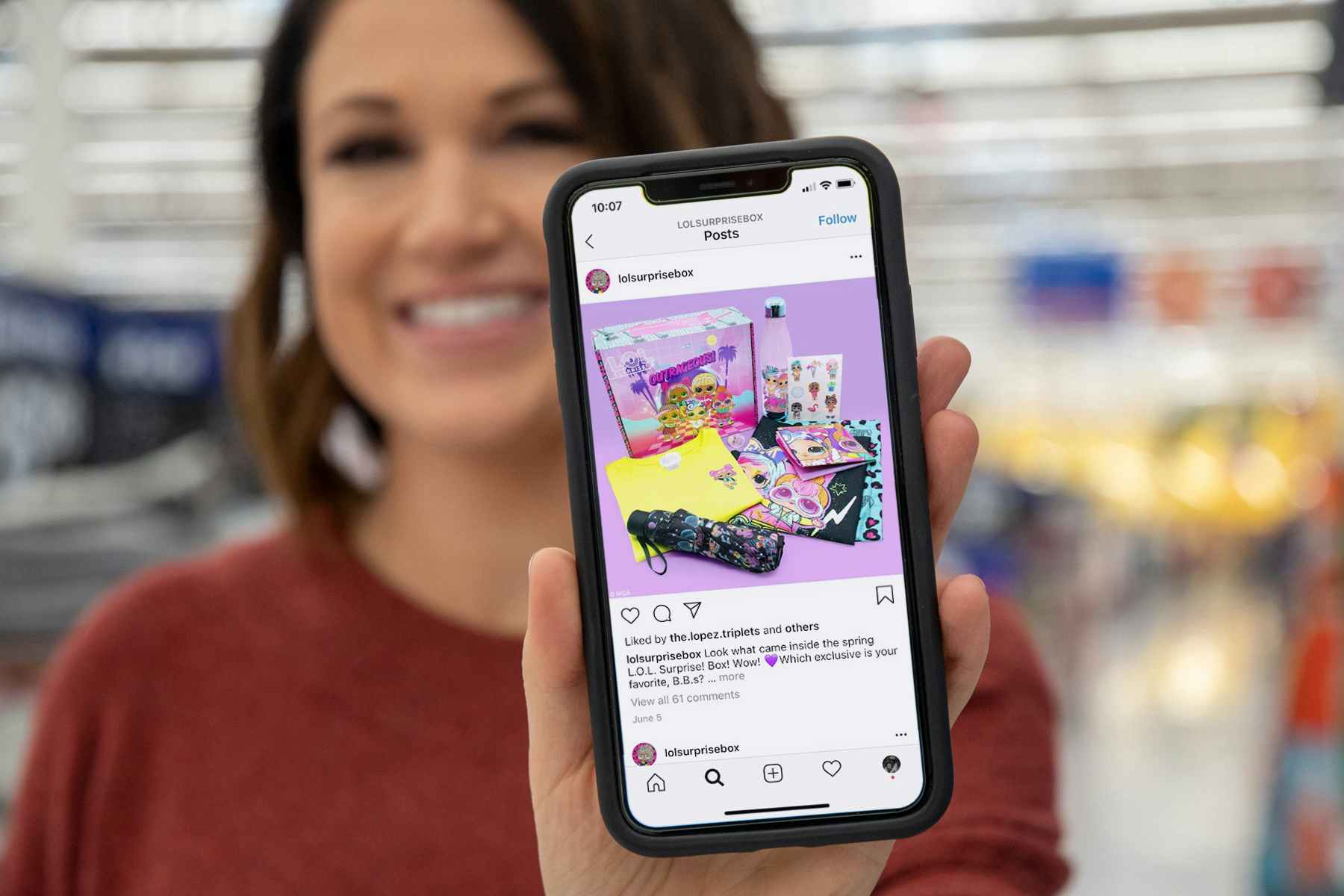 Woman holding up phone in walmart with LOL surprise subscription box on instagram