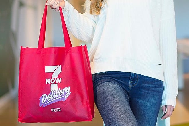 A person holding a 7-Now 7-Eleven delivery bag.