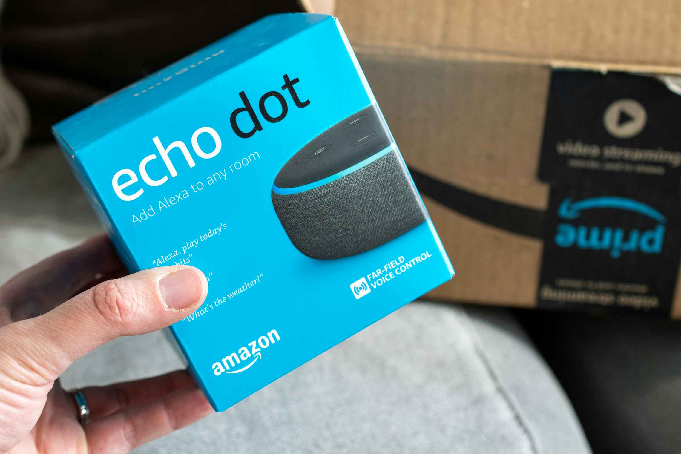 An Amazon Echo Dot in front of an open delivery box.