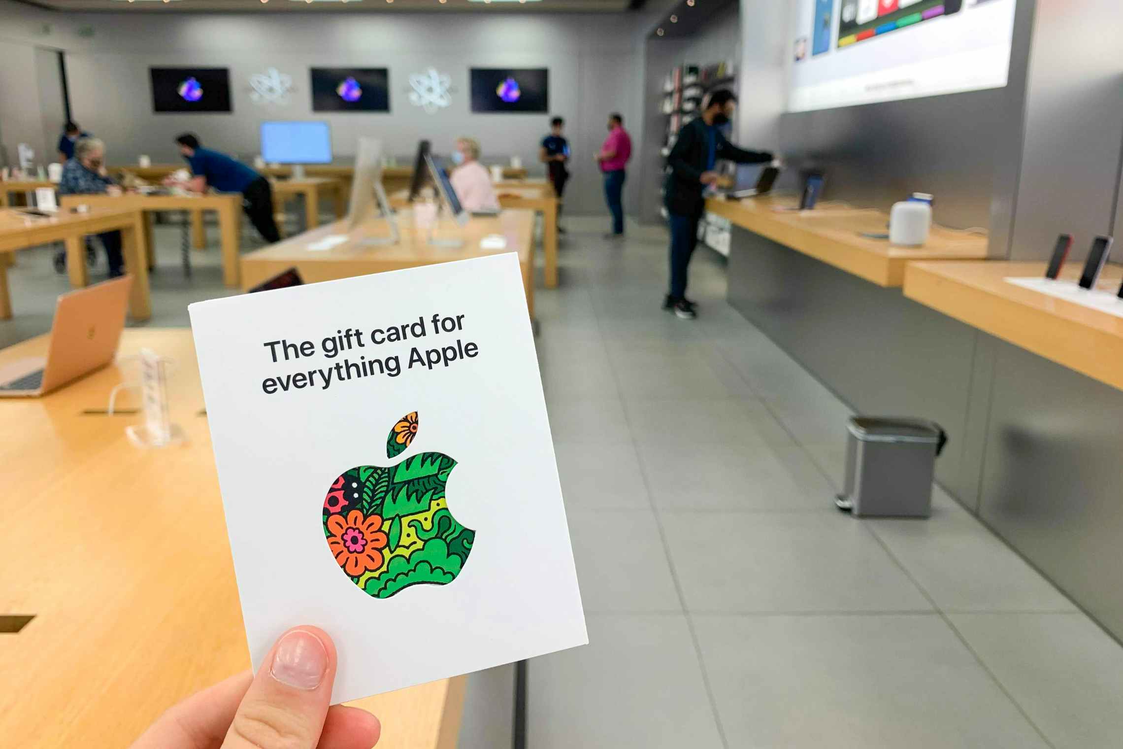 Someone holding up an apple gift card in the apple store