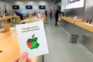 Someone holding up an apple gift card in the apple store