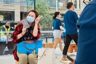 A person holding an iPhone box and doing a peace sign with their hand