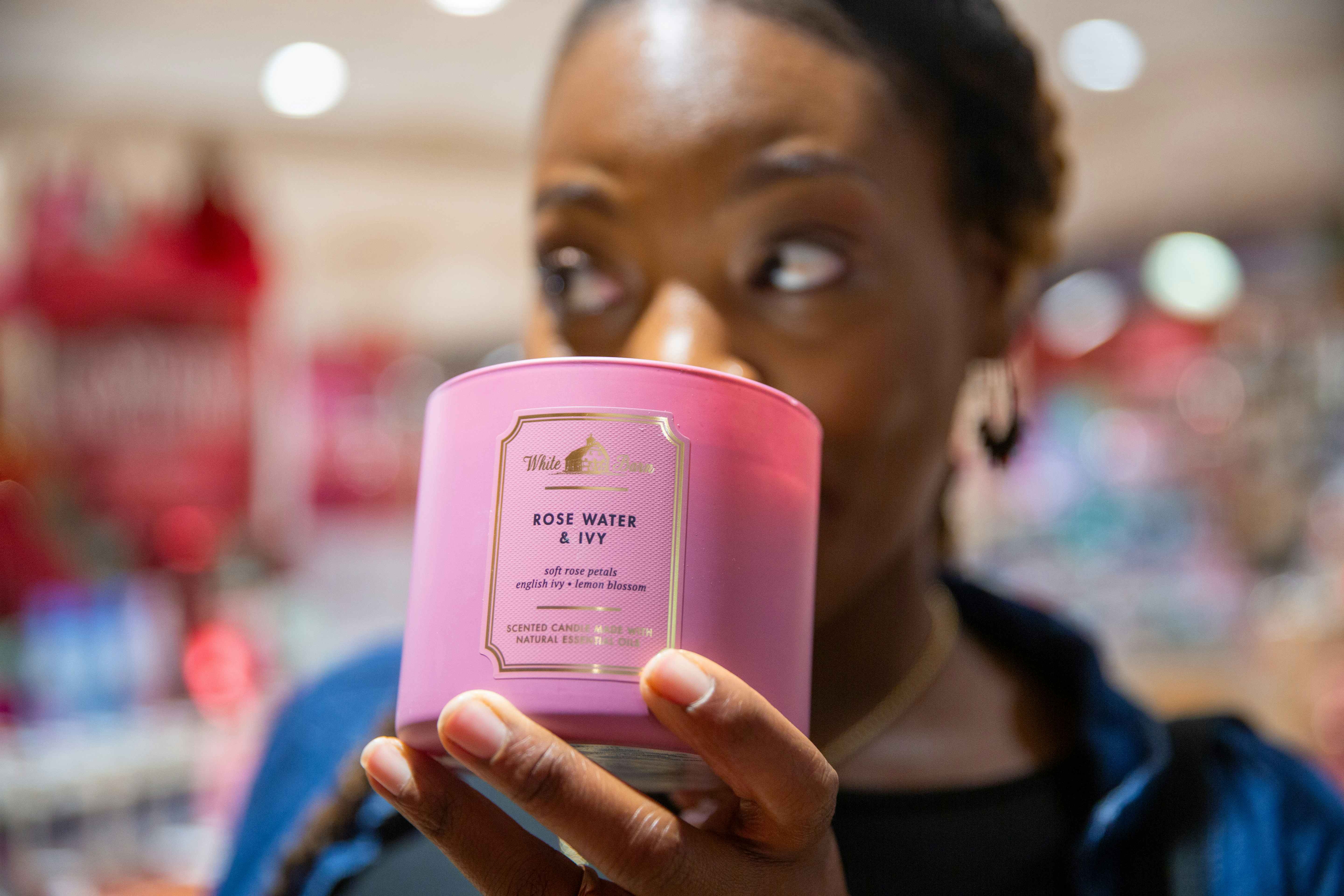 Person holding up a pink candle from Bath and Body works to their nose to smell