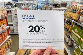 A person holding a Bed Bath & Beyond coupon inside the store.