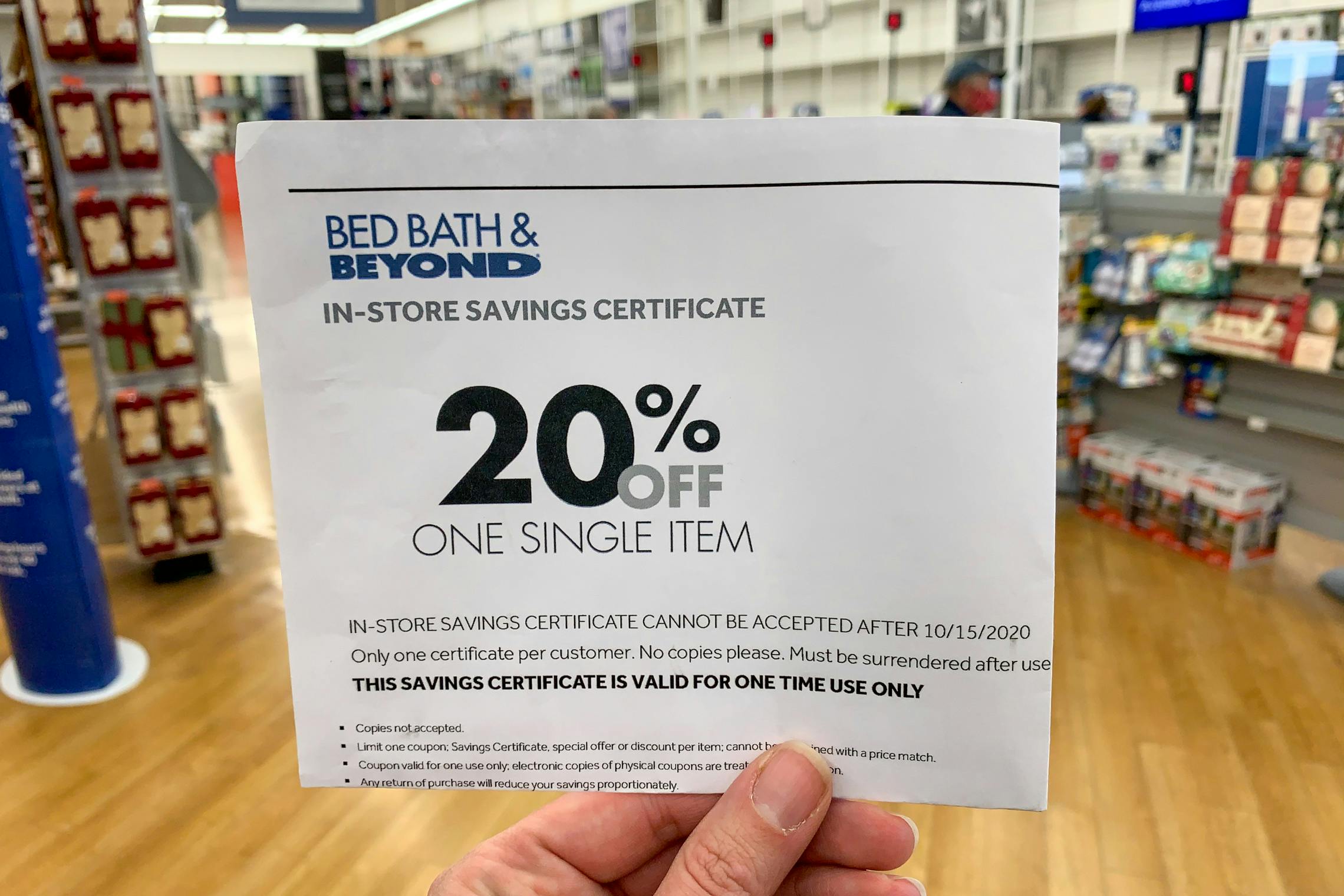 A person holding a Bed Bath & Beyond coupon inside the store.