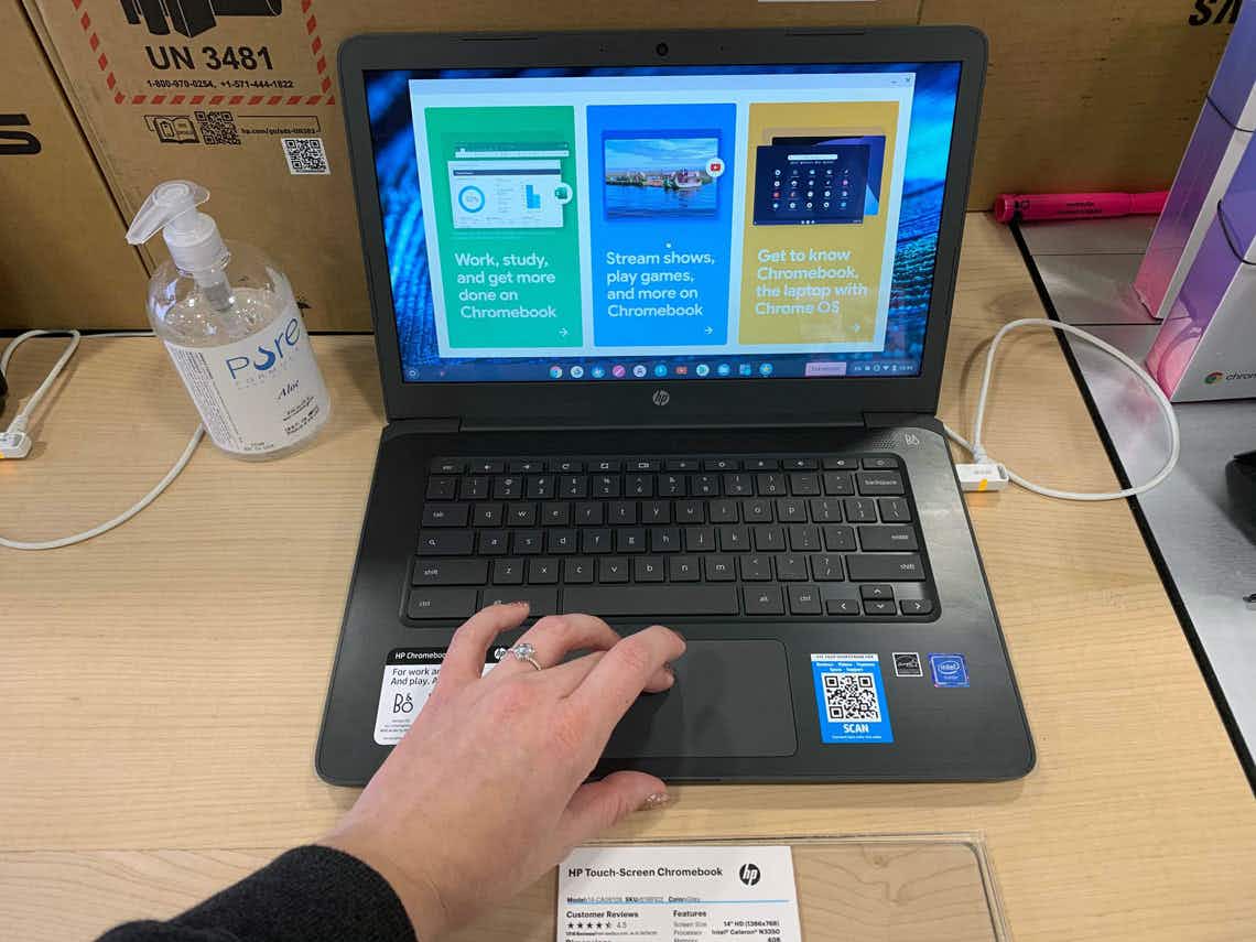 A person's hand using the touchpad on a HP Chromebook display laptop inside BestBuy.