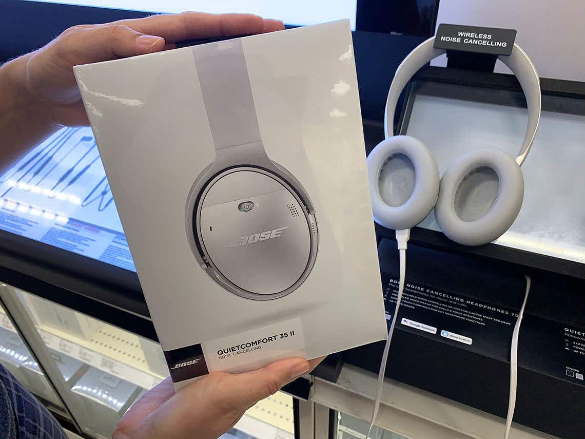 a person holding bose headphone in store in front of display 