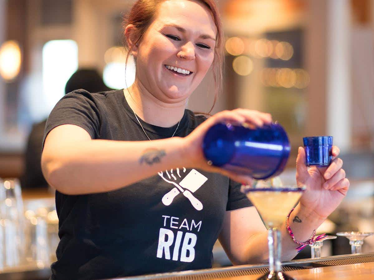A Chili's bartender pouring a margarita into a glass.