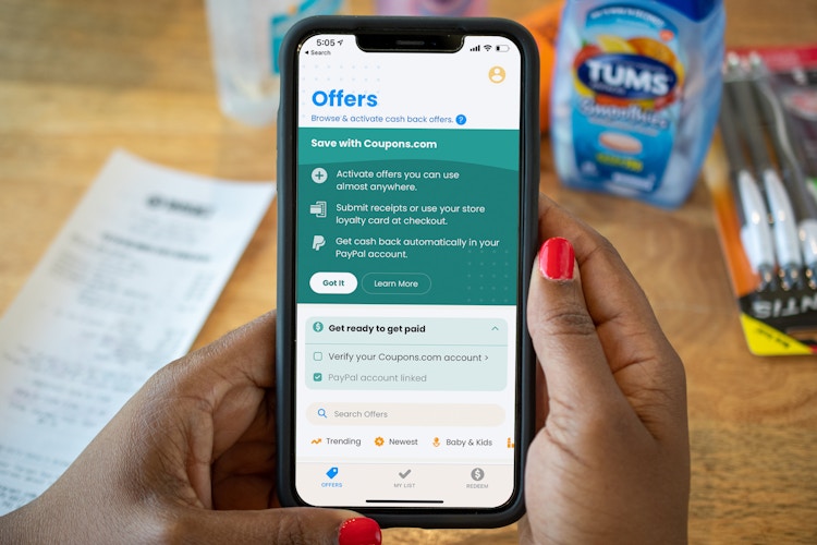 Coupons.com app on a cell phone with a receipt and products in the background