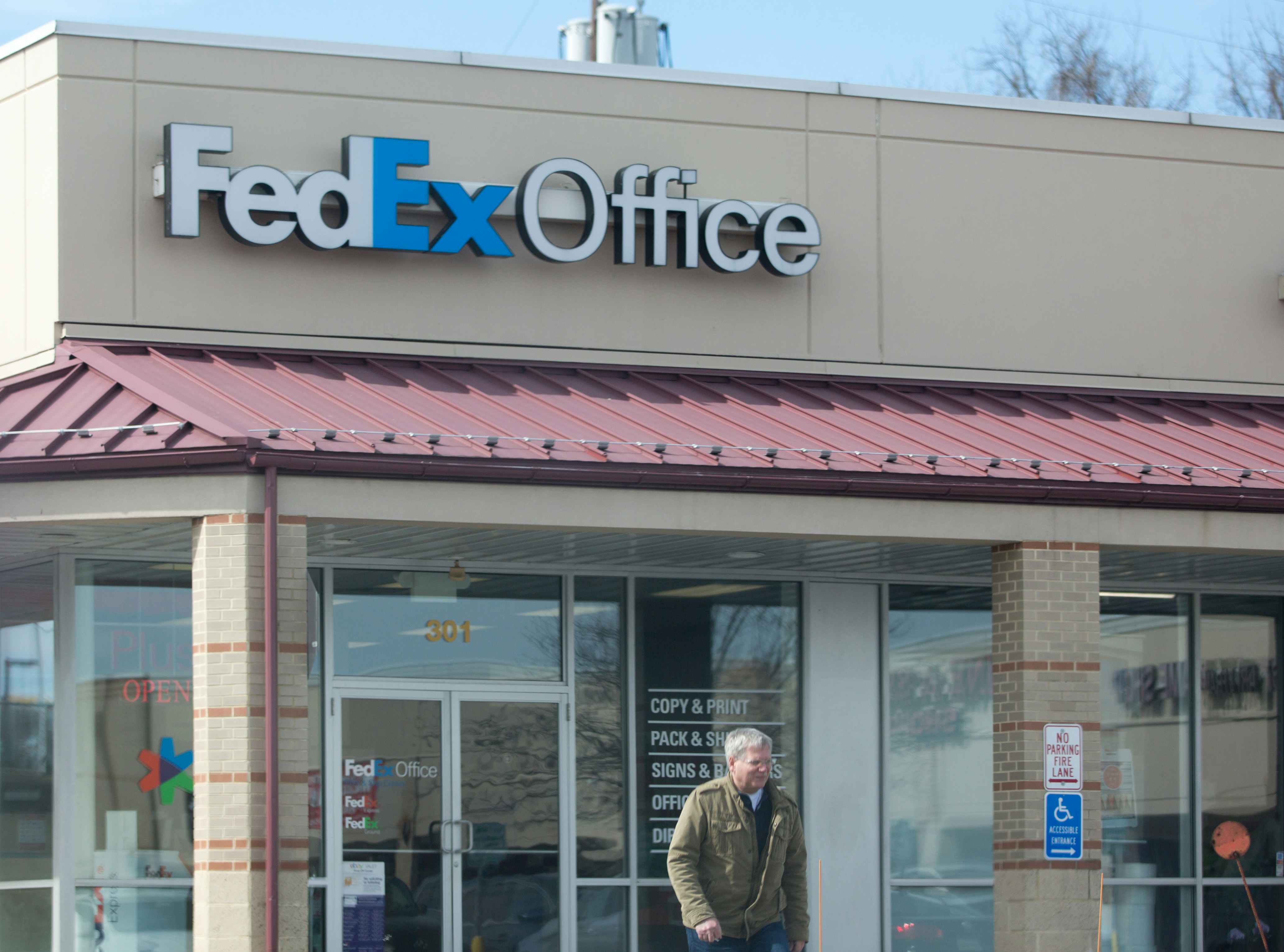 A man exiting a FedEx store.