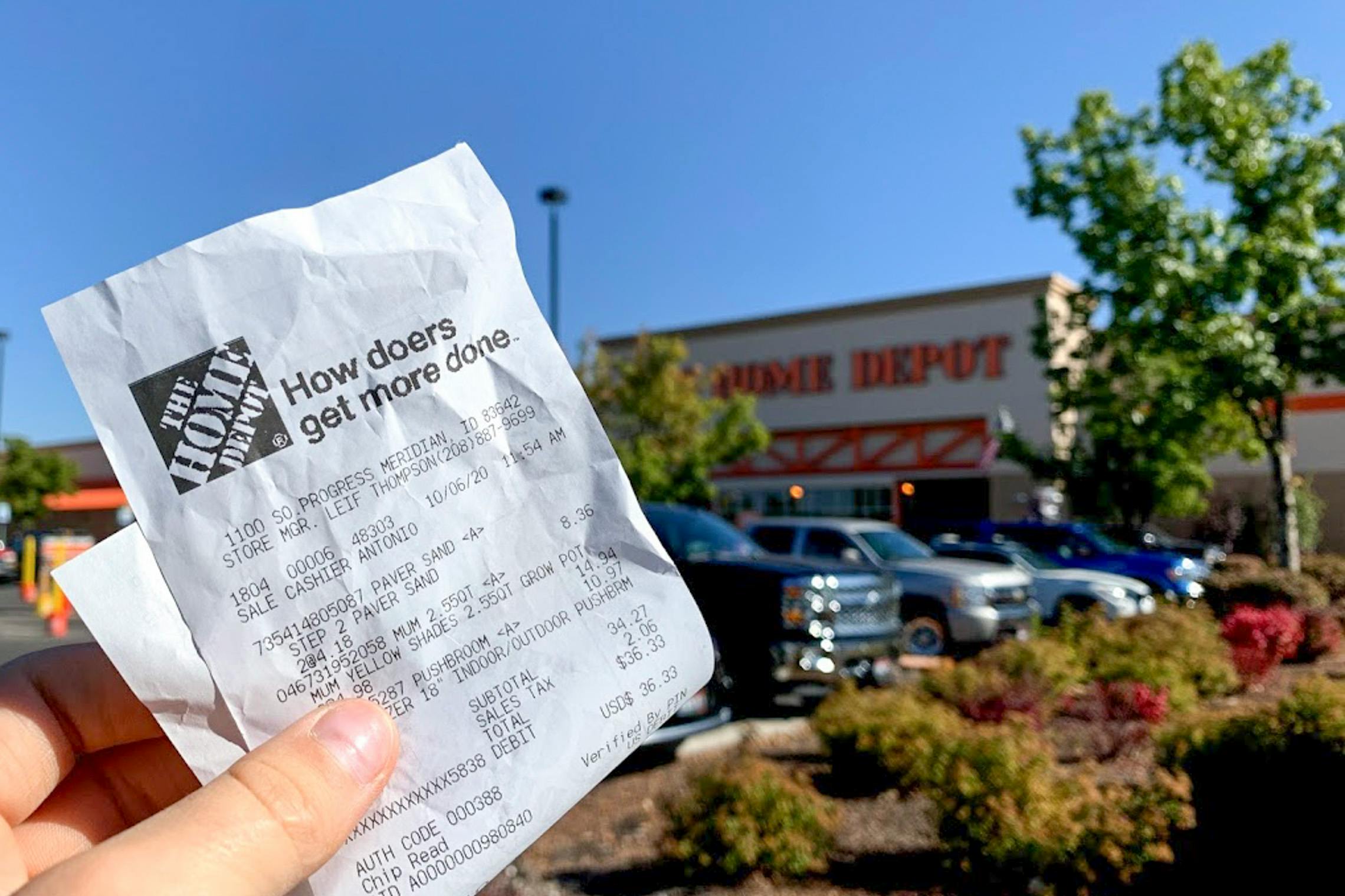 Someone holding up their Home Depot receipt in front of a Home Depot store.