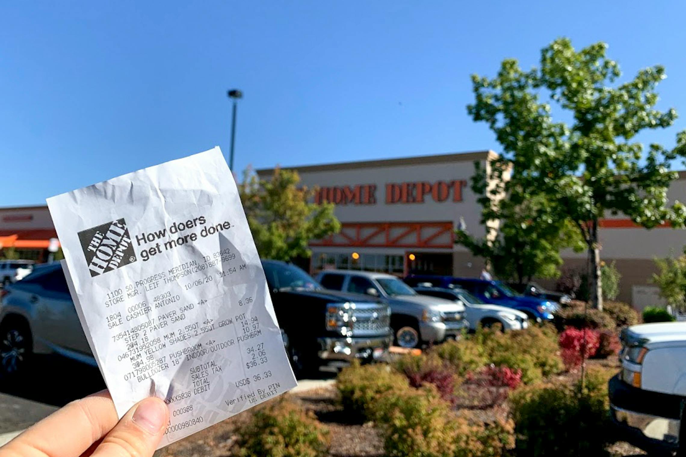 Someone holding up their receipt in front of Home Depot store front