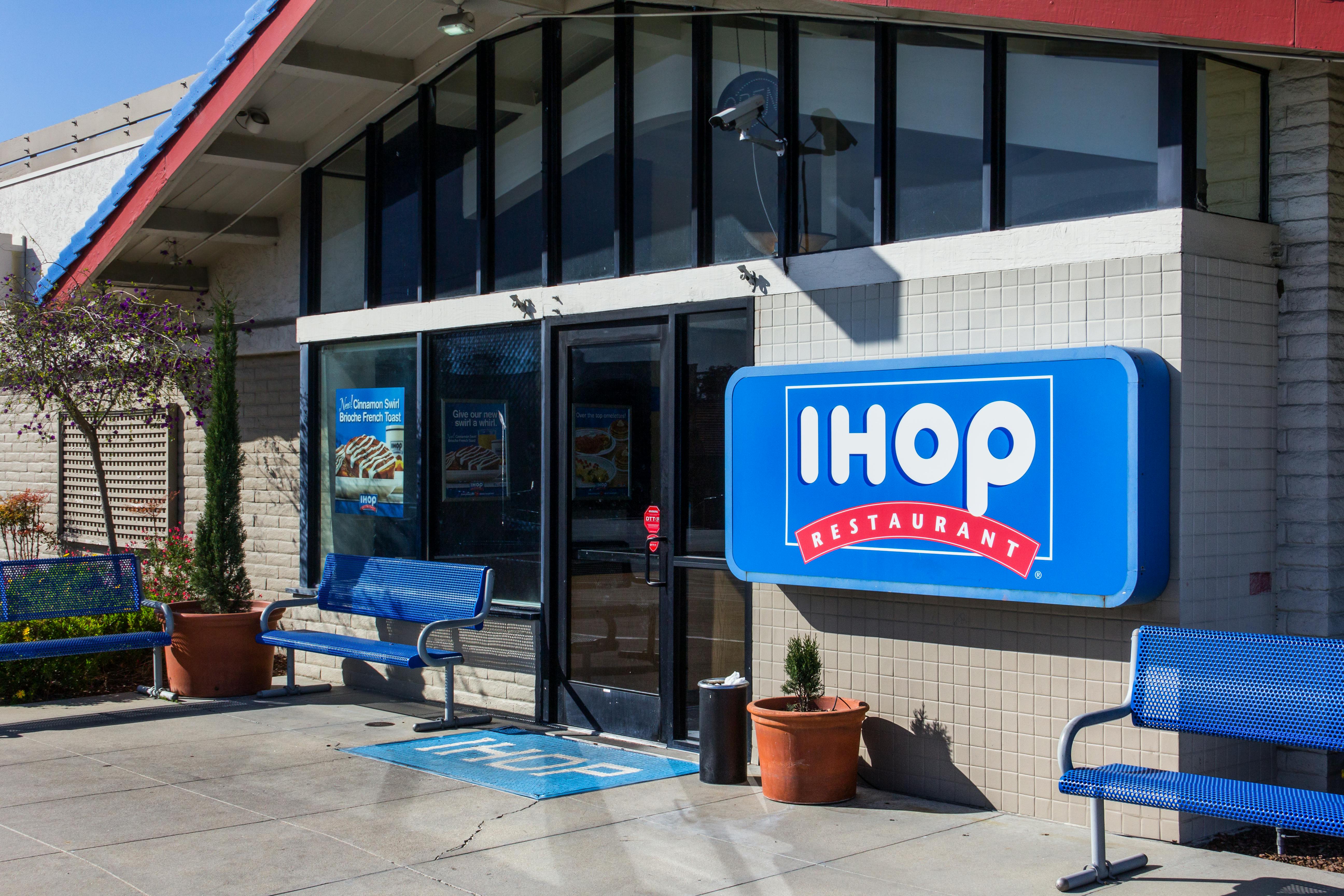 An IHOP restaurant building storefront and sign with benches outside of the door.