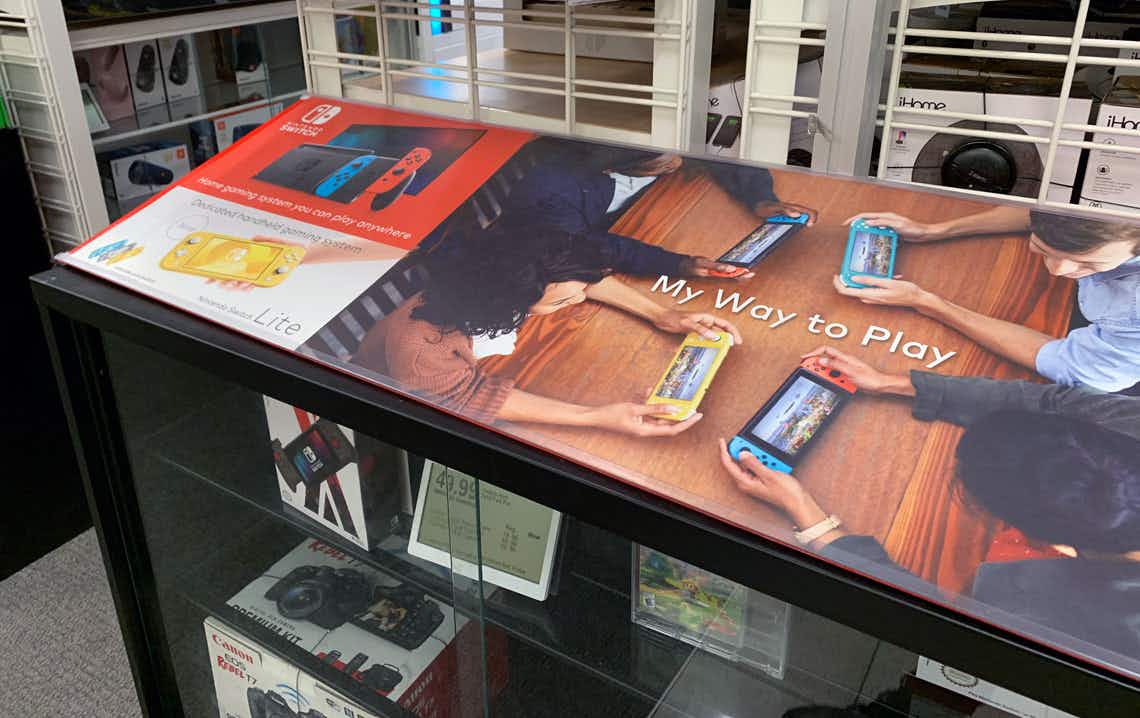 a display clase with a picture of people playing on the nintendo switch and nintendo switches behind glass