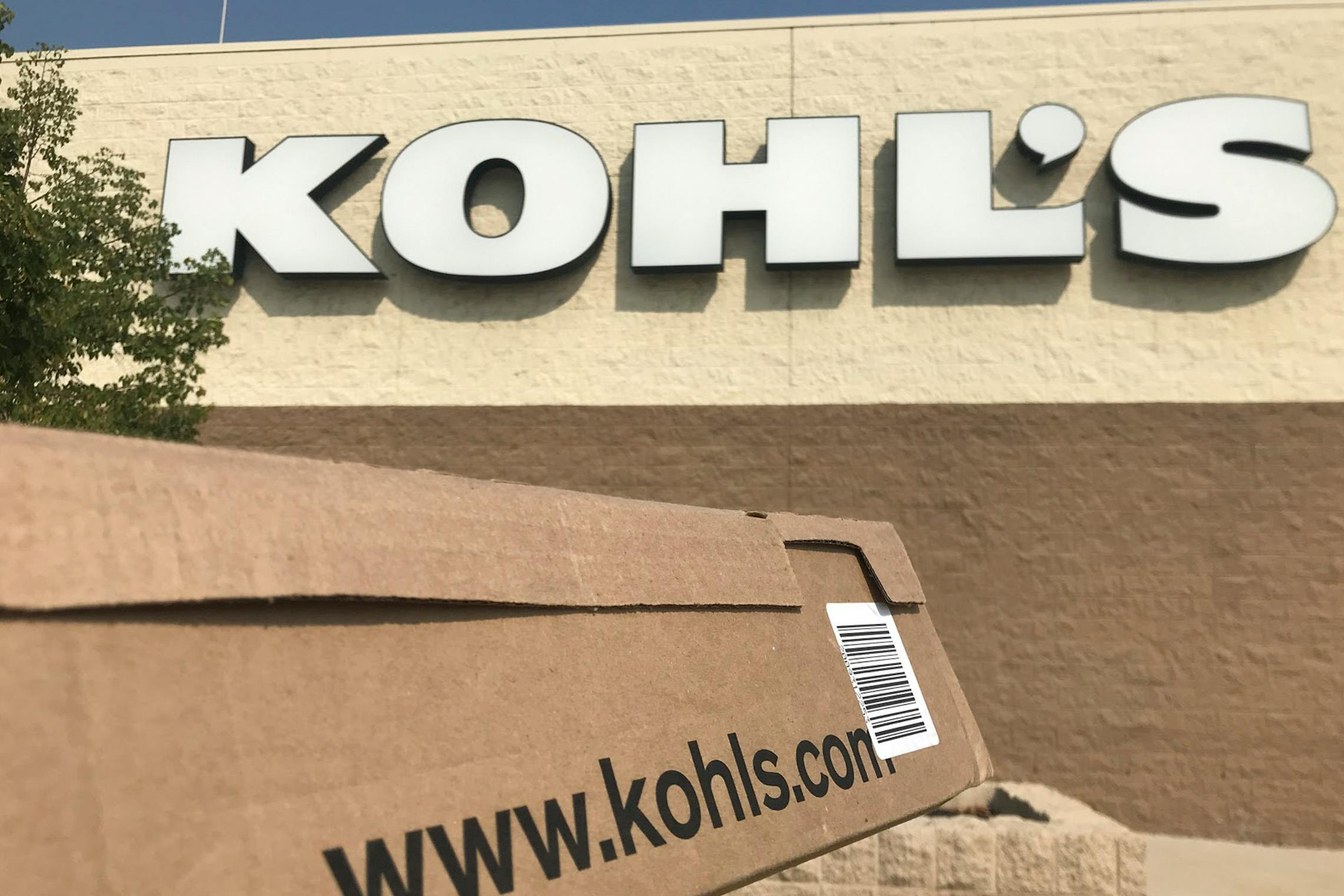 Woman holding Kohls delivery box in front of kohls store front