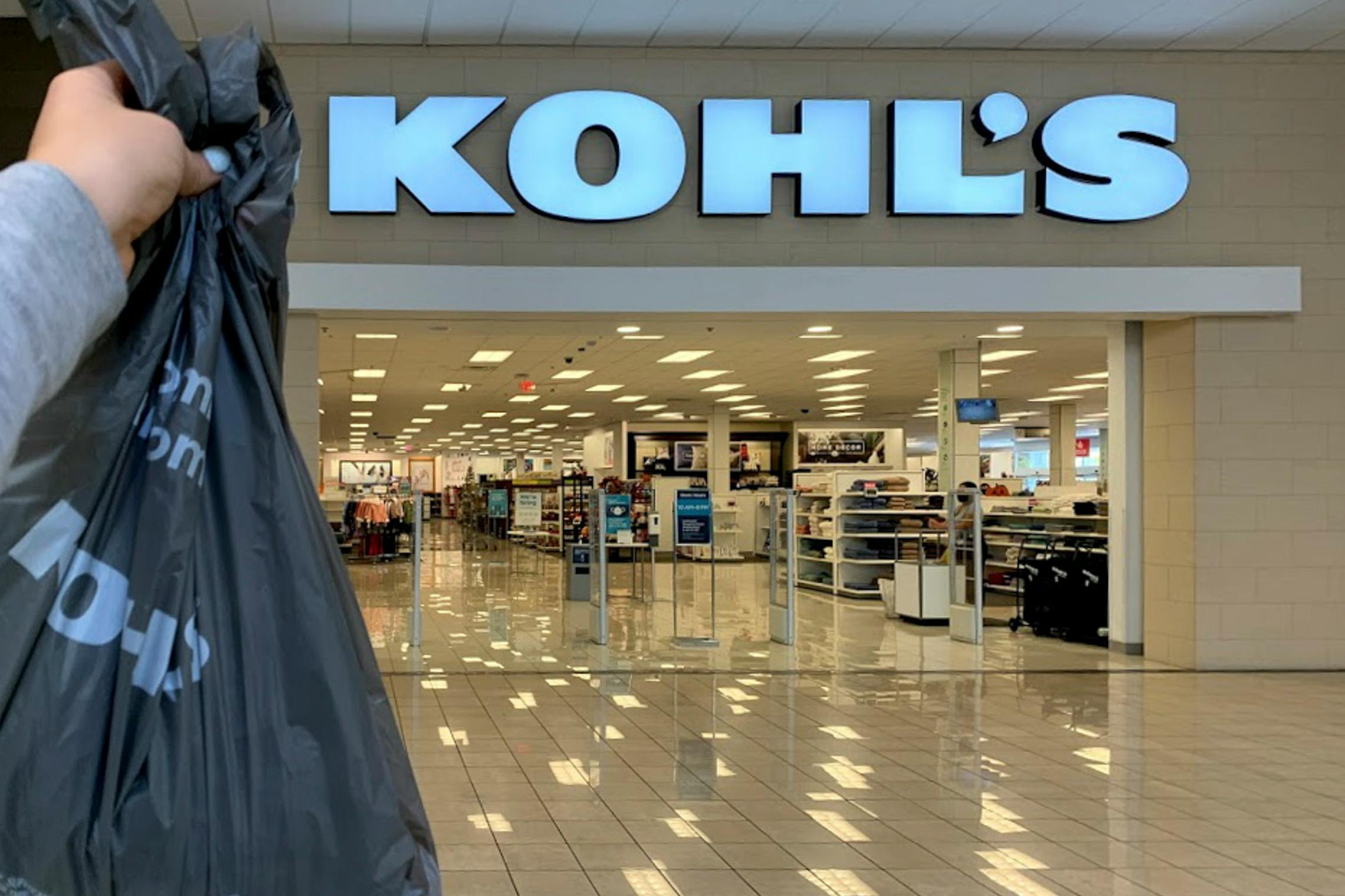 Woman holding up shopping bag in front of kohls store front