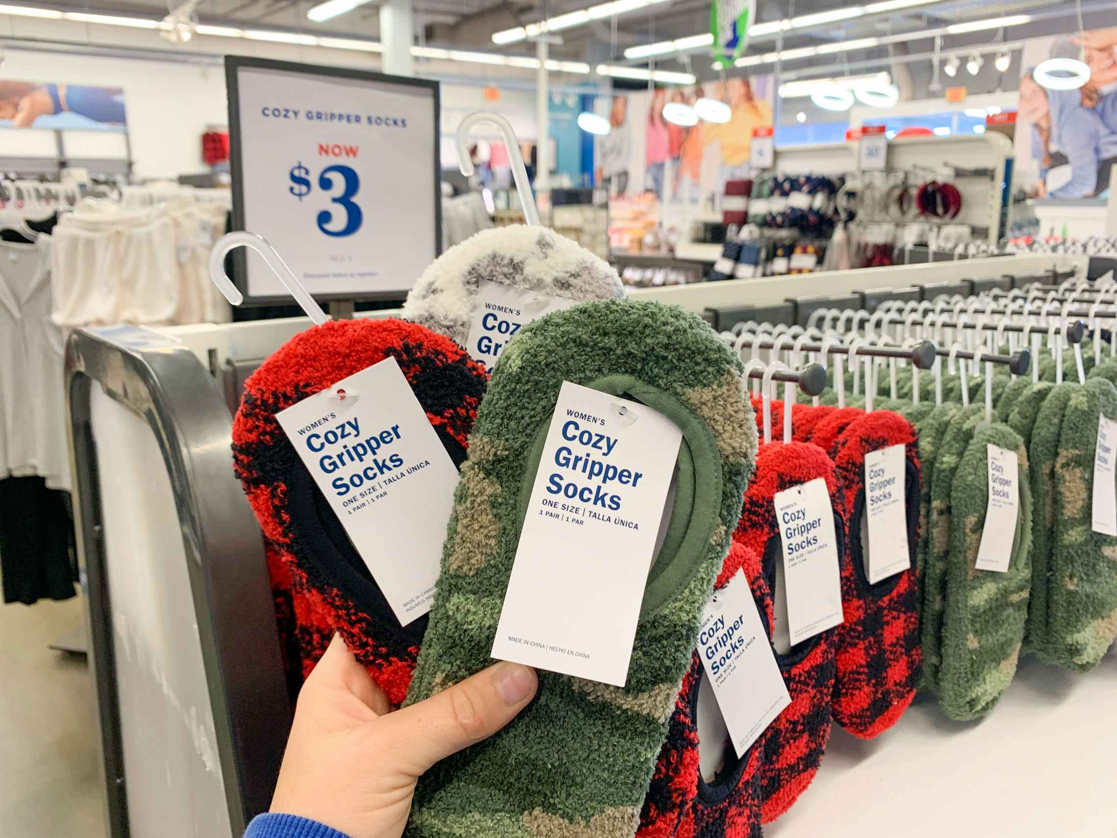 A person's hand holding up cozy gripper socks in Old Navy on Black Friday.