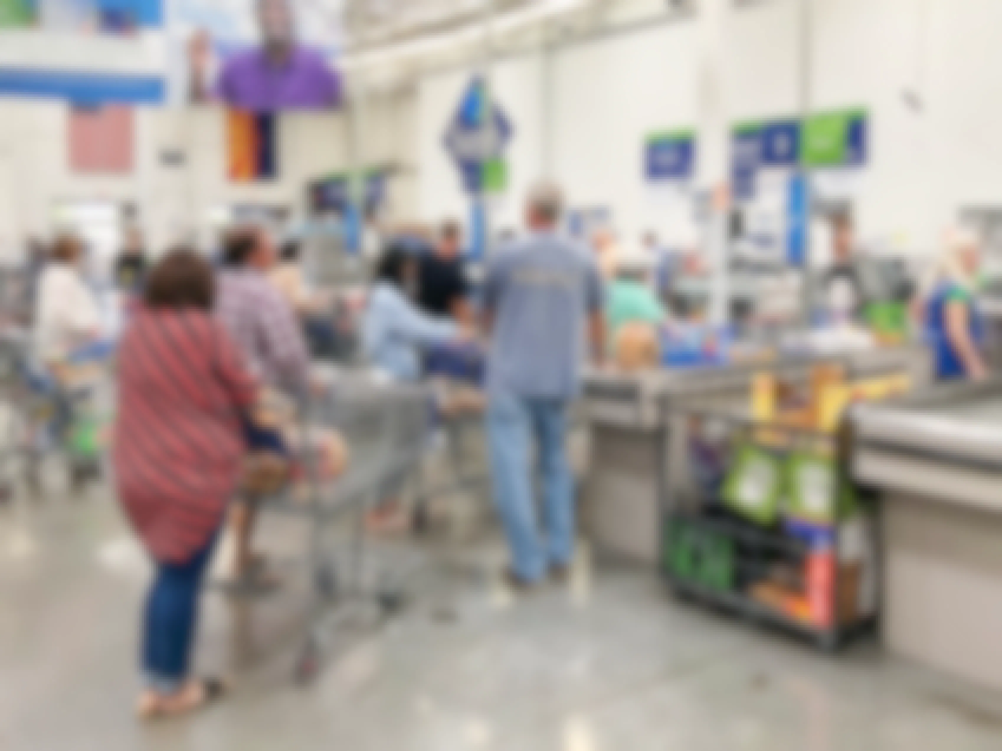 best things to buy at sam's club - Sam's Club members standing in line for checkout with carts full of groceries and other items.