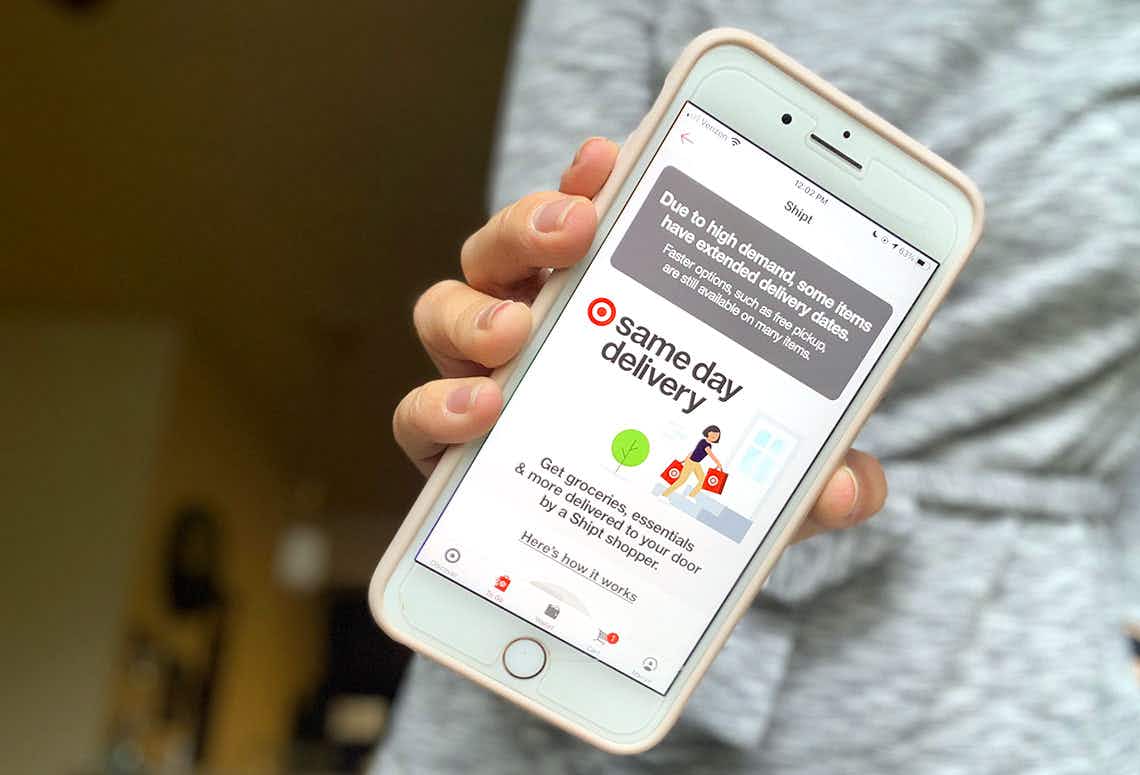 a woman holding up her smartphone showing the Shipt same-day delivery page in the Target app