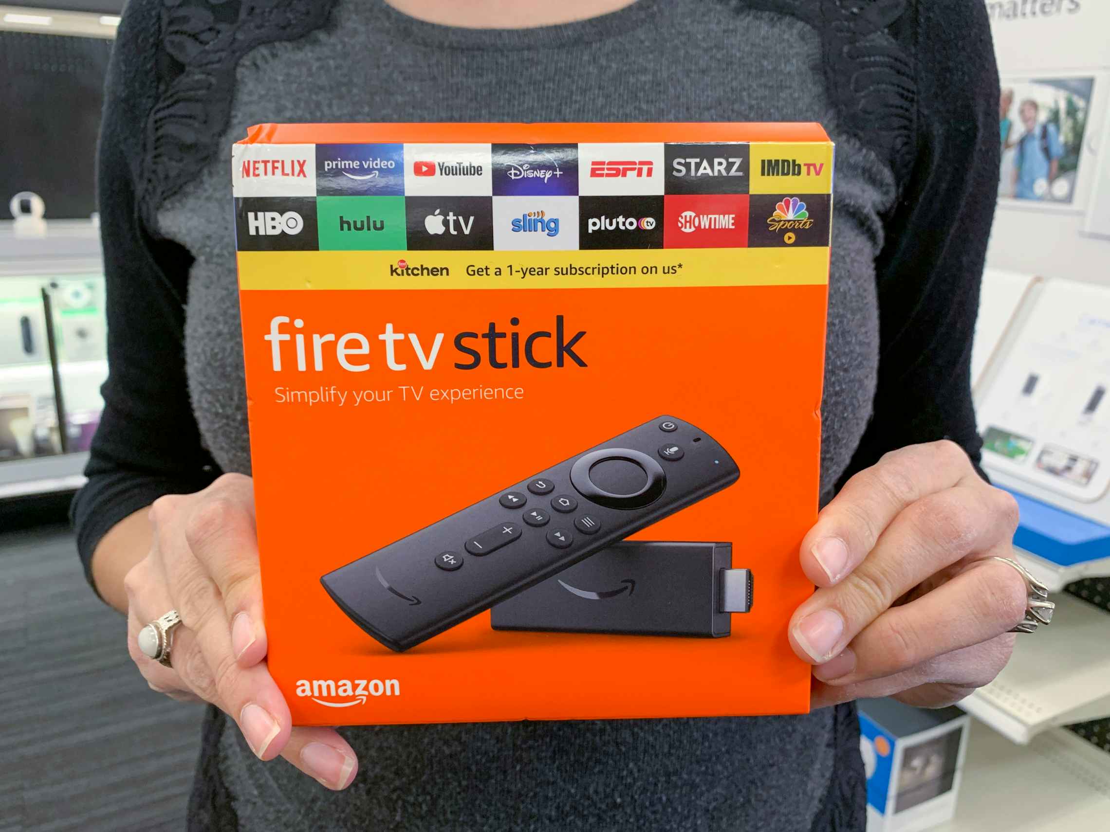 A woman holding an Amazon Fire TV Stick in a store.