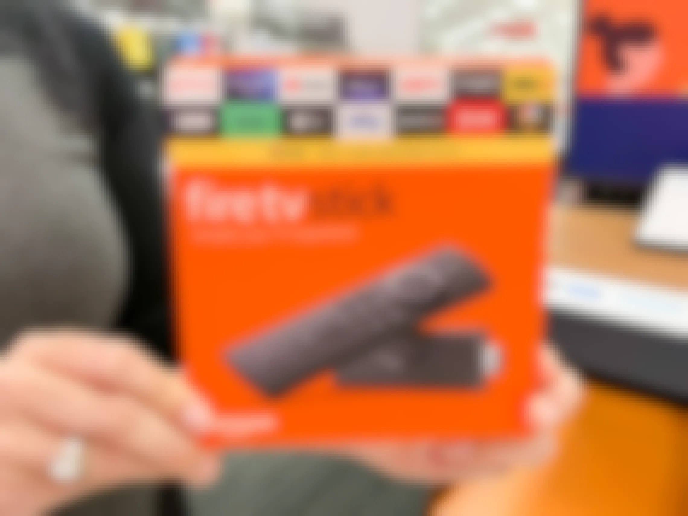 A person holding up an Amazon Fire TV Stick inside of a store.