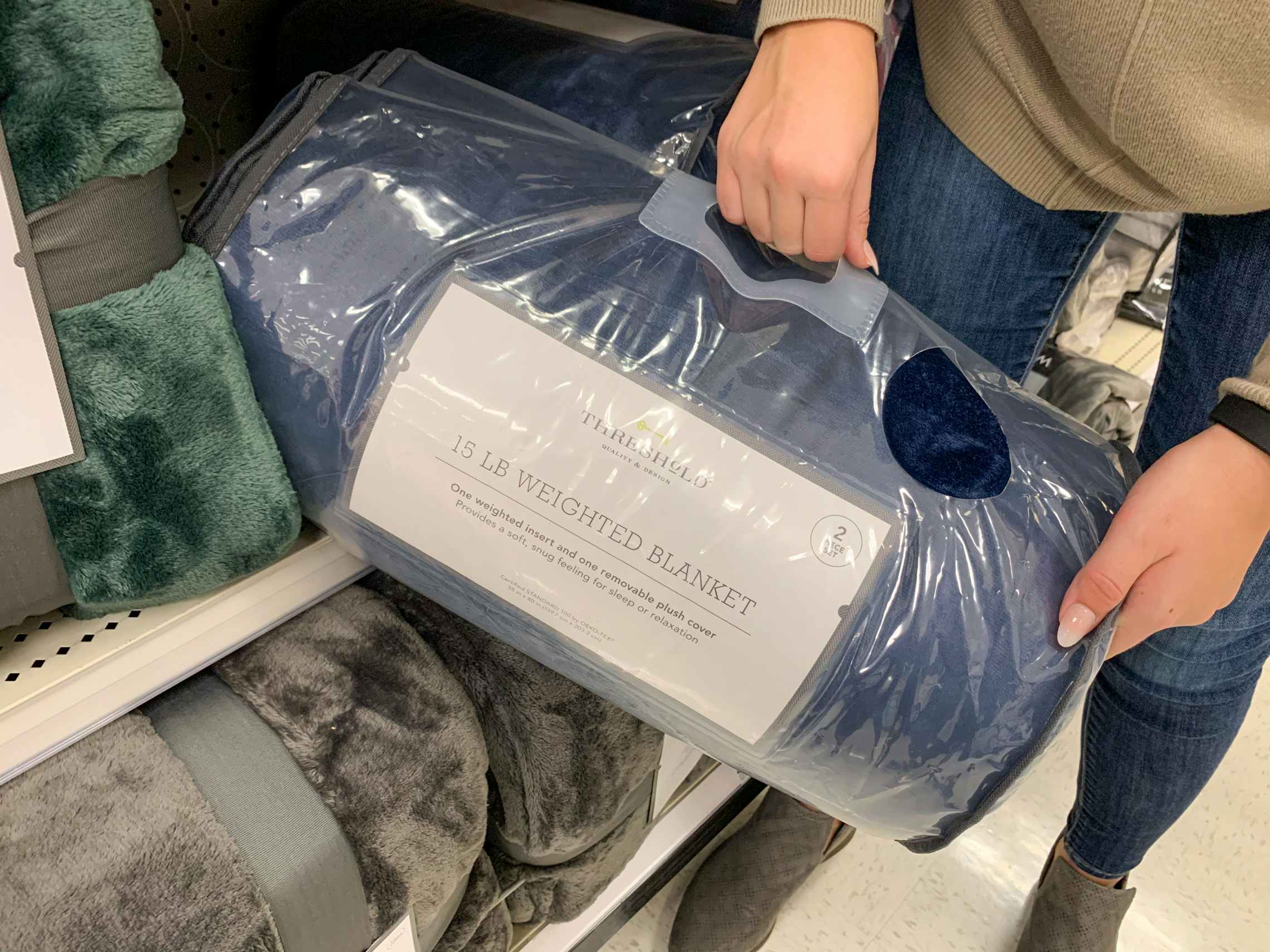 A woman pulling a blue weighted blanket off a shelf