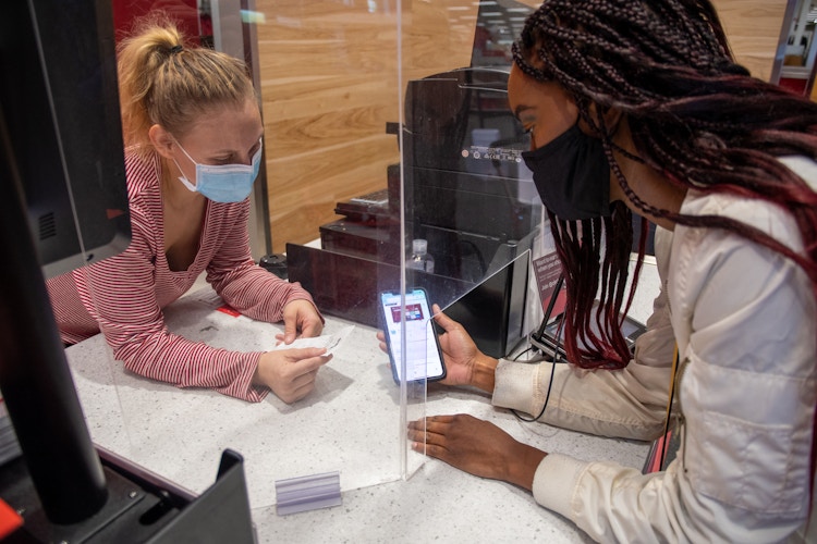 A person showing a phone and a receipt to an employee for a price adjustment at the Target guest service counter.
