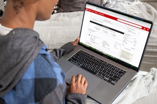 A woman looking at a laptop computer with a target shopping cart filled with products on the screen.