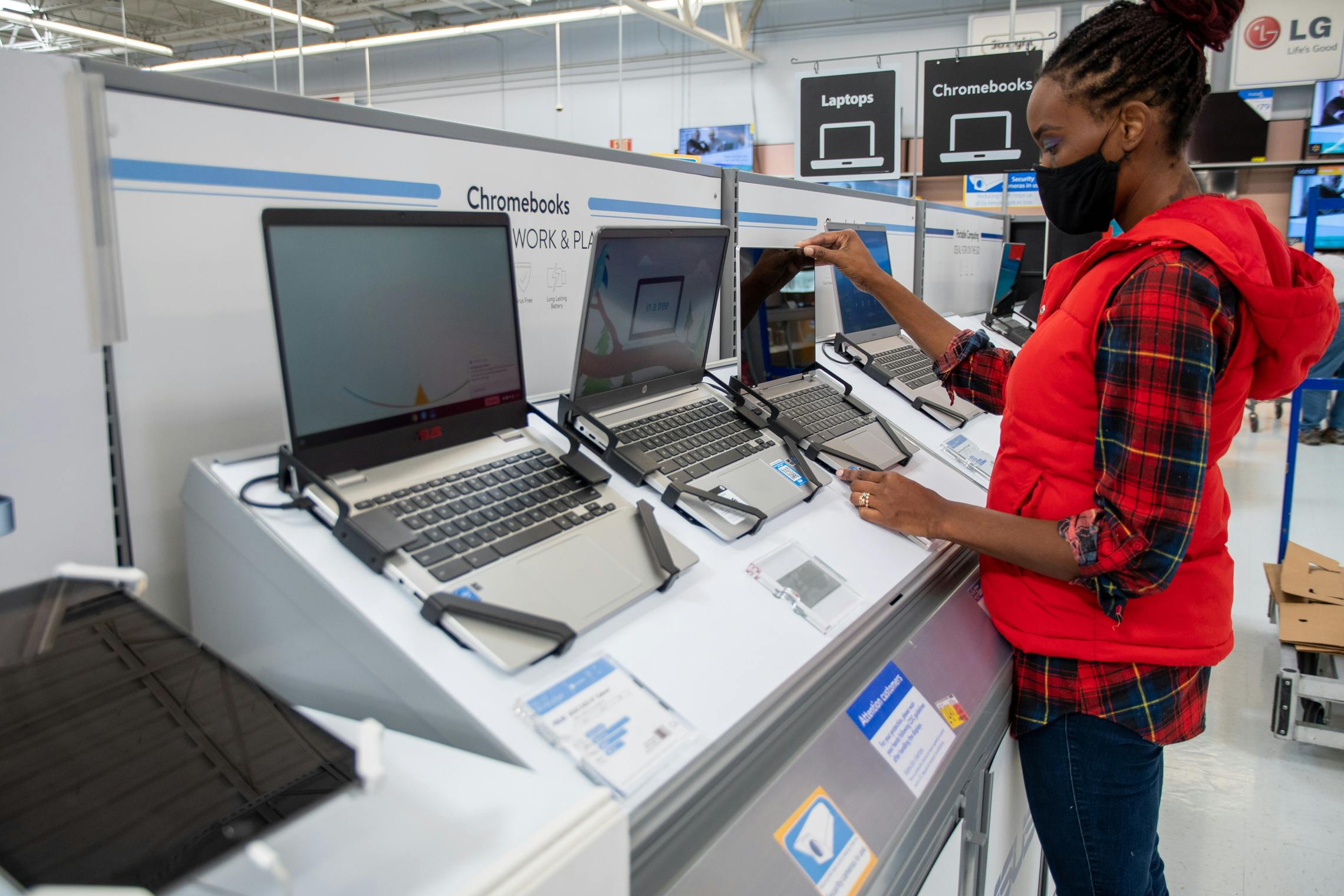 A woman looking at Chromebook laptop computers at Walmart.