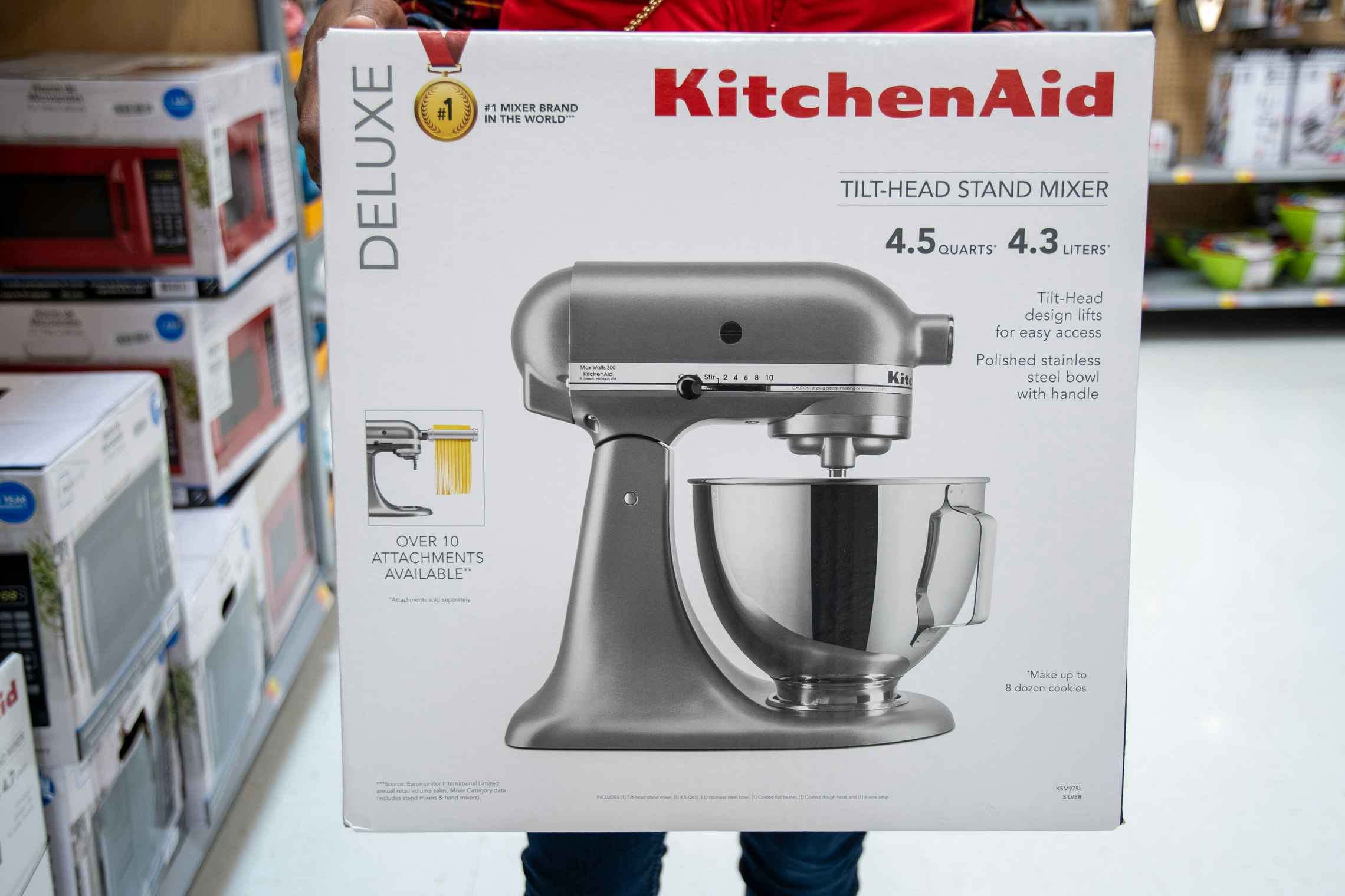 A woman holding a box containing a KitchenAid stand mixer