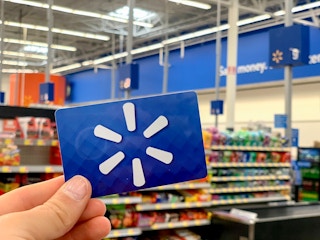 Walmart gift card held up in store with Walmart logo in background