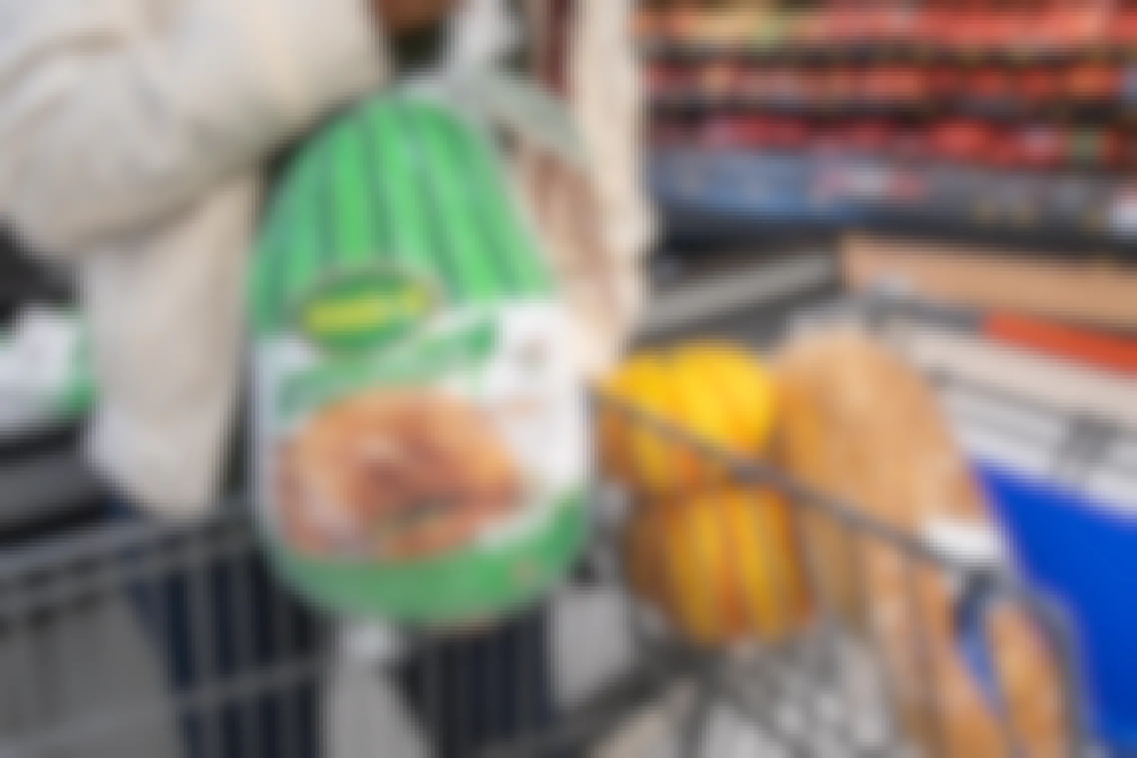A woman putting a frozen turkey into a shopping cart.