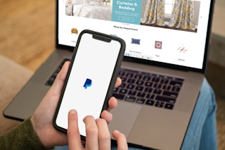 Paypal app on a cell phone with wayfair.com open on a laptop in the background.