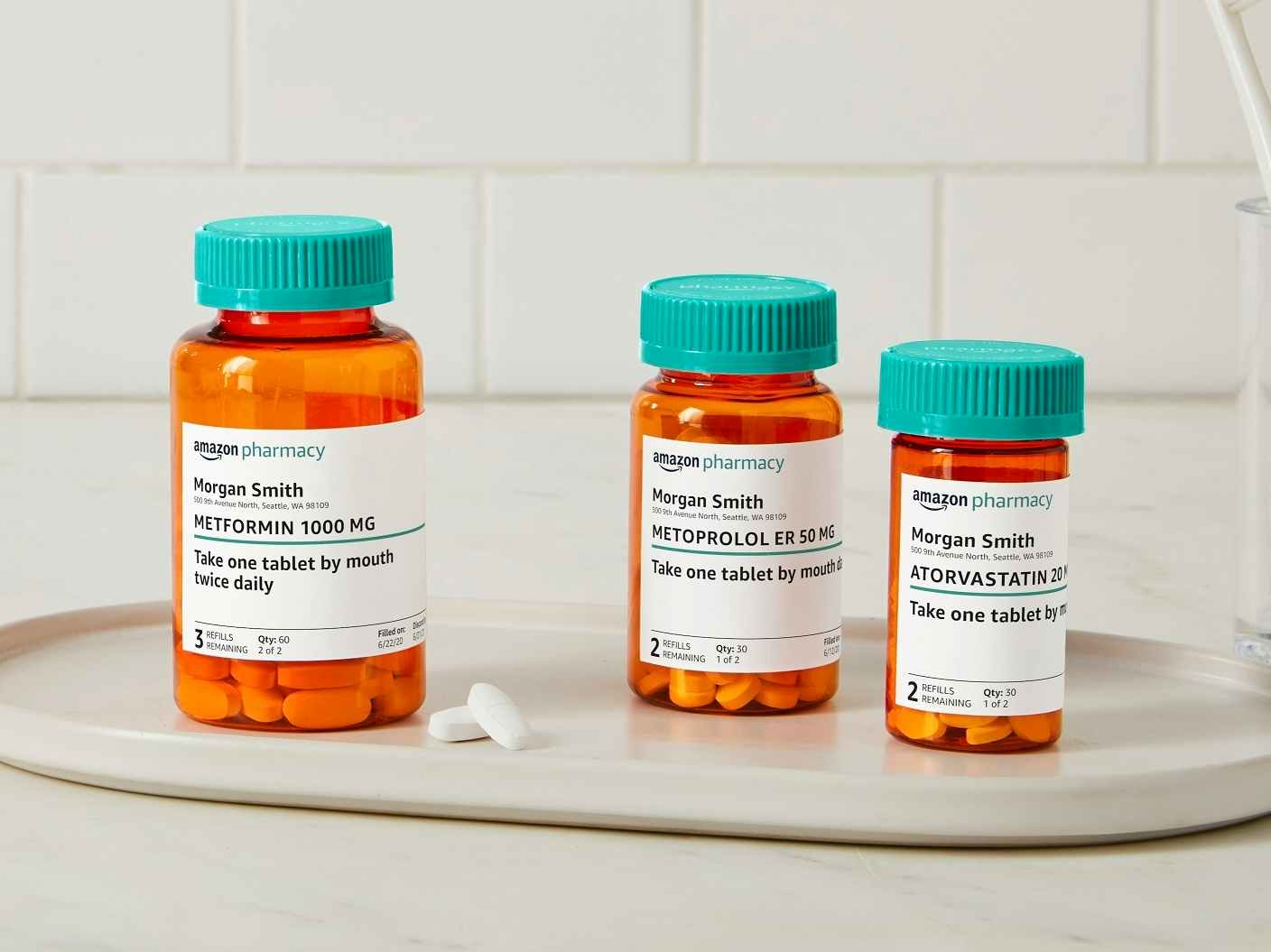 Three Amazon Pharmacy Rx pill bottles sitting on a tray on a bathroom counter.