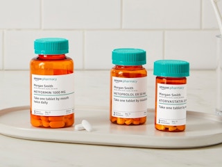 Three Amazon Pharmacy Rx pill bottles sitting on a tray on a bathroom counter.