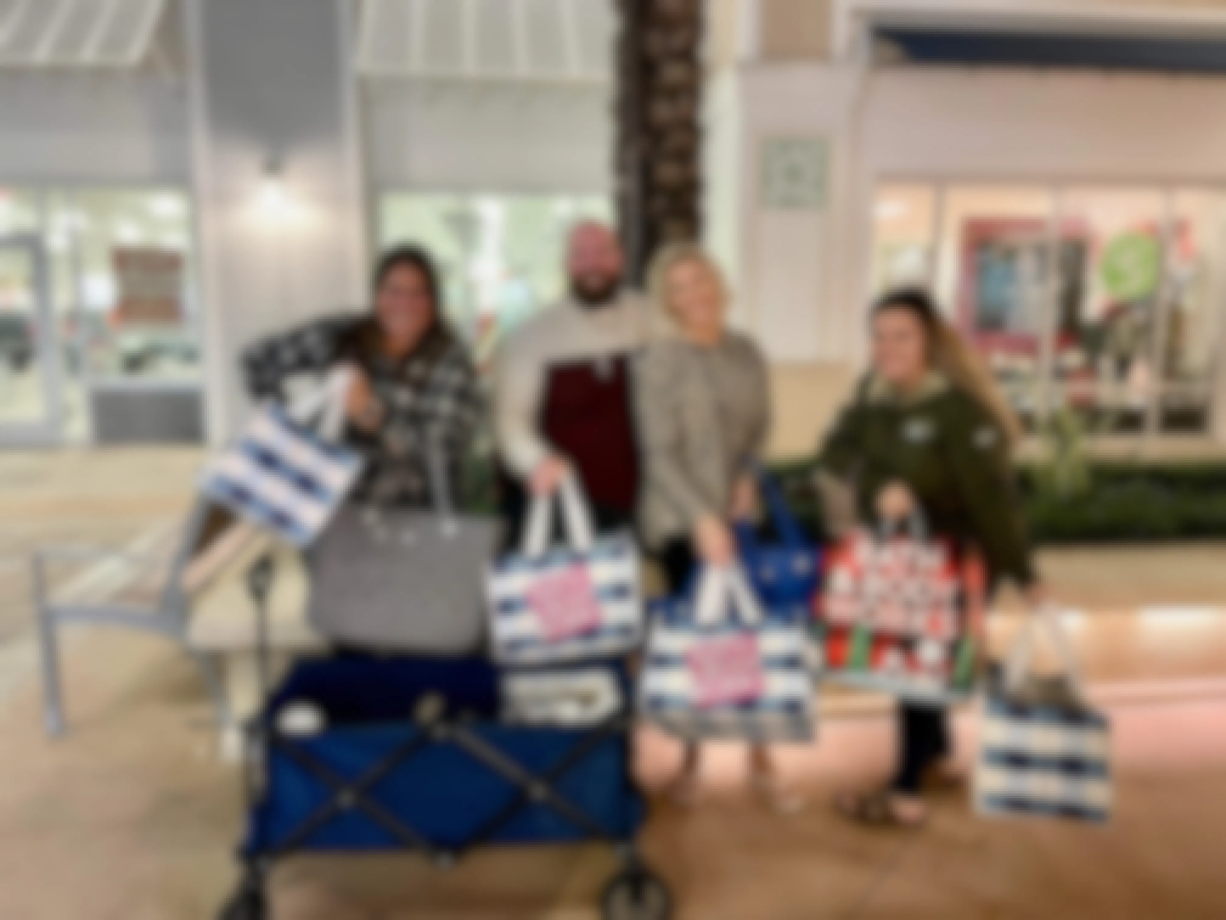 4 people holding bags filled with Bath and Body Works candles. 