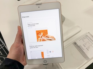 a hand holding an apple ipad mini on display at best buy