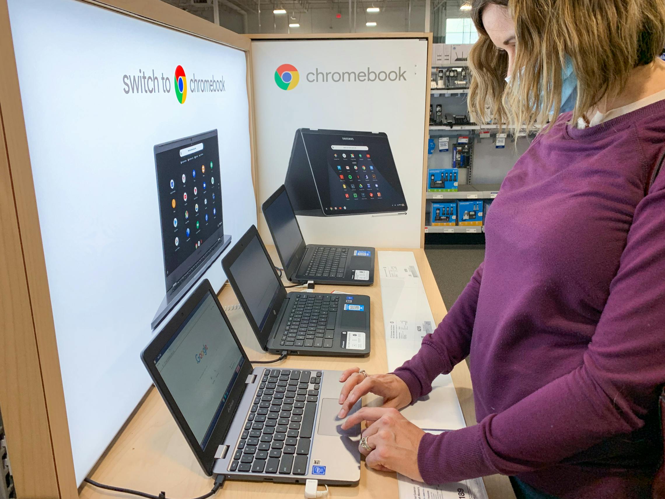 A woman looking down and using the touch pad on a Chromebook on display at Best Buy.