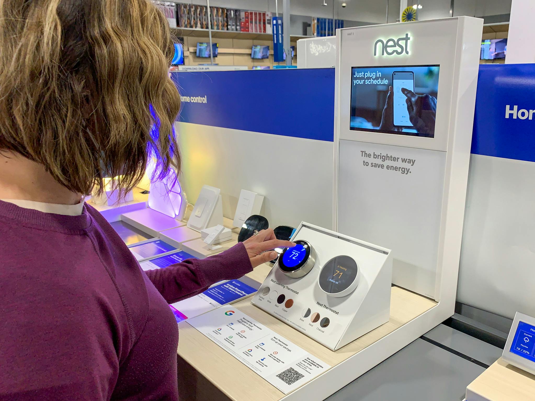 A woman testing out a Nest thermostat on the Nest display inside Best Buy.
