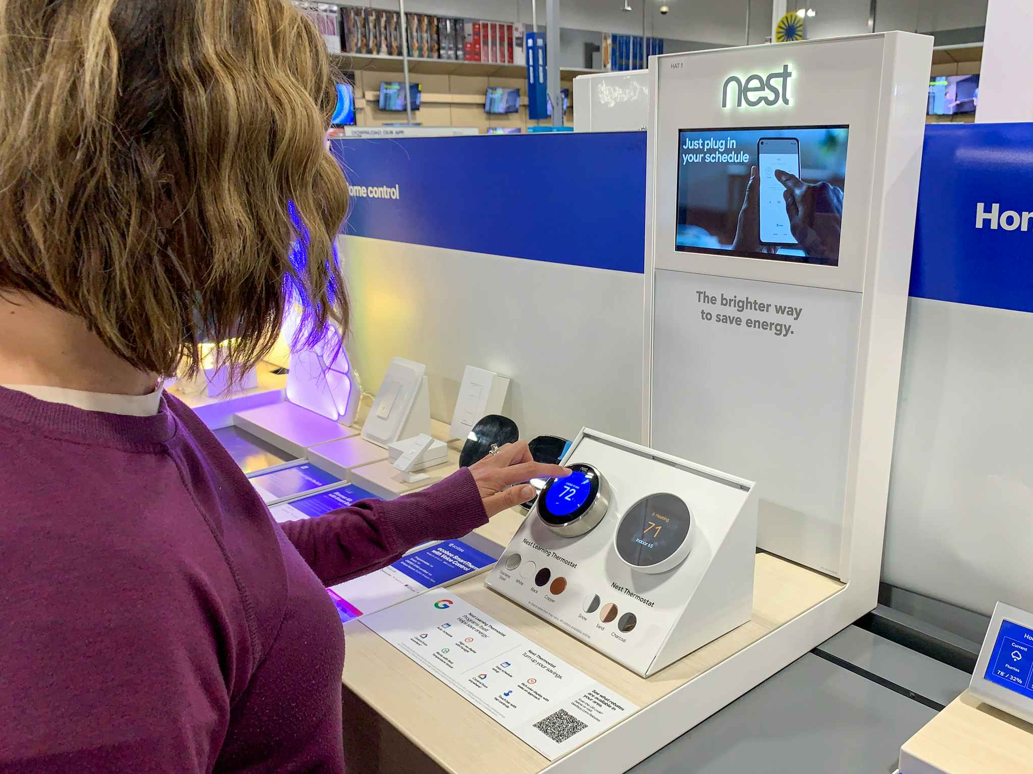 A woman testing out a Nest thermostat on the Nest display inside Best Buy.
